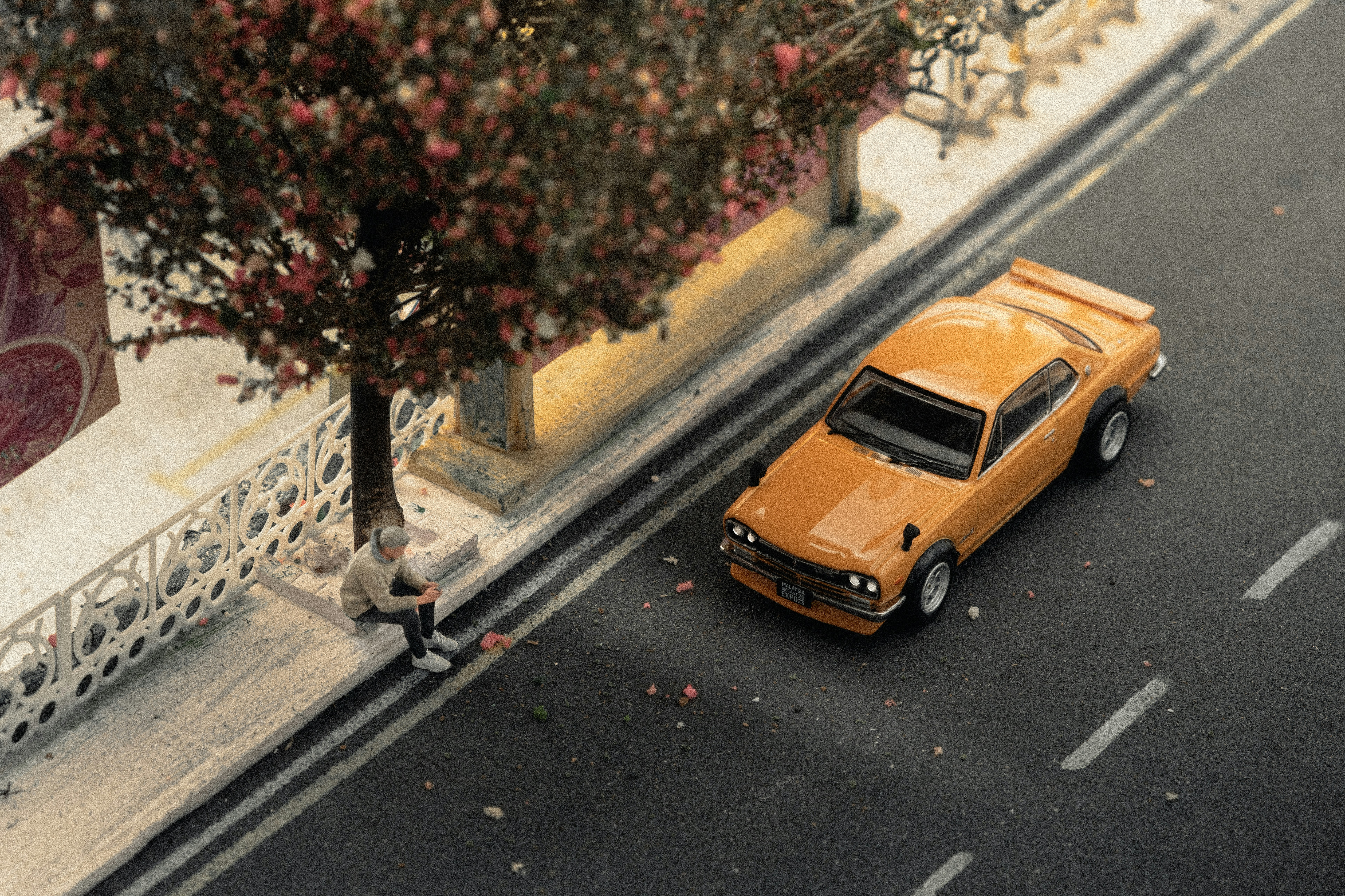 Scena in miniatura con auto e persona per strada.