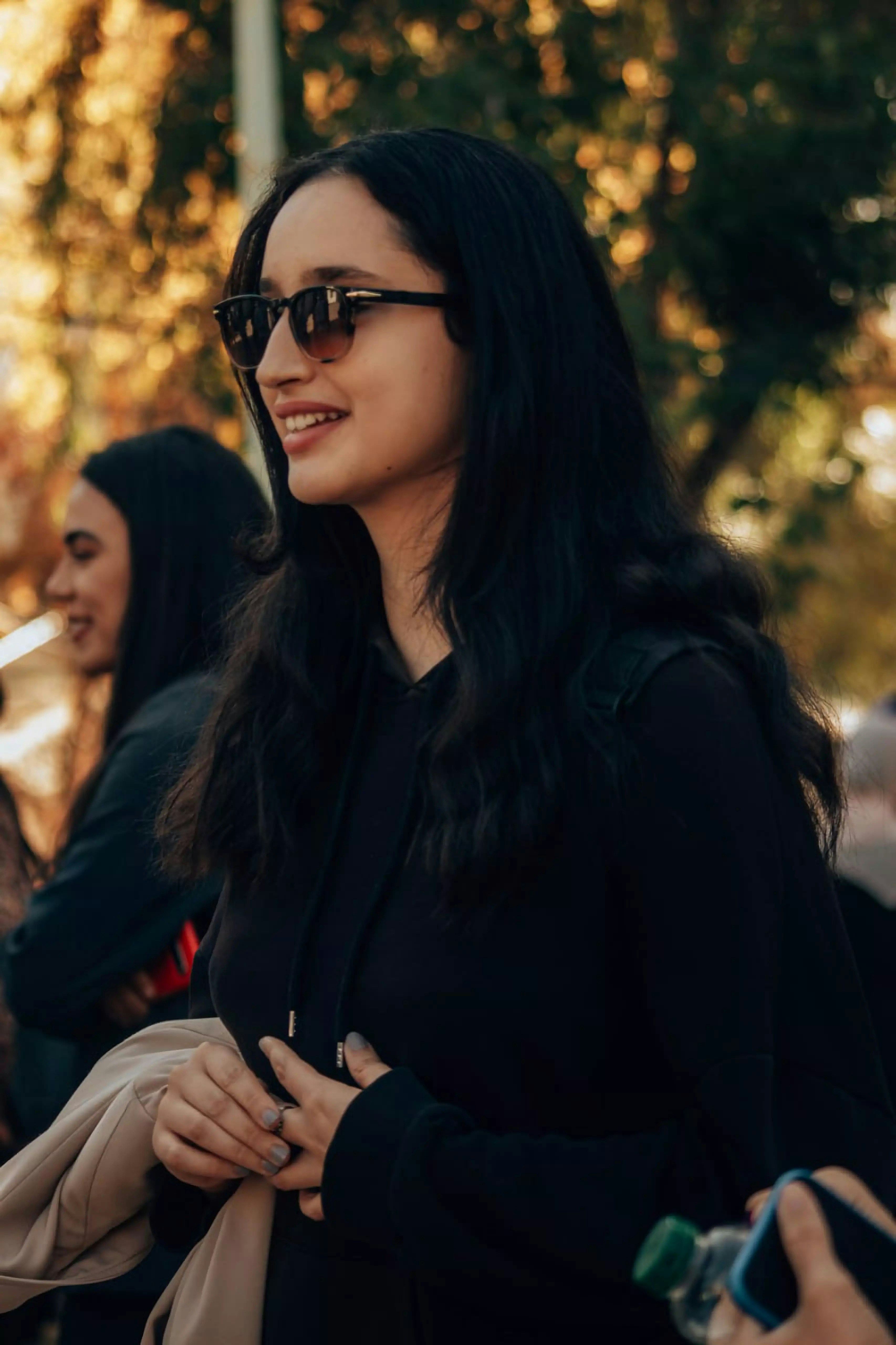 Woman with sunglasses smiles outdoors.