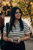 Smiling woman with glasses and a striped shirt.