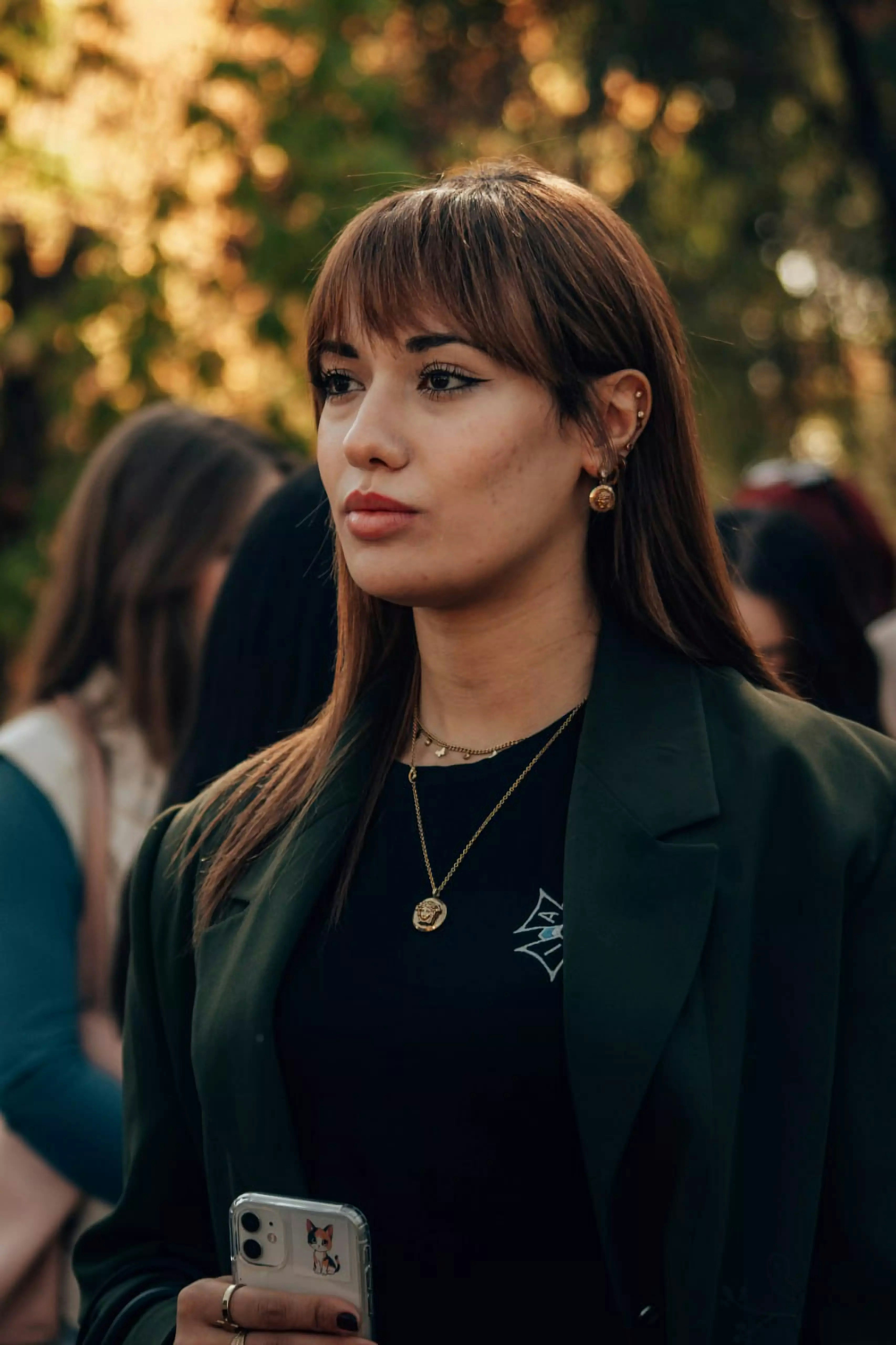 Woman with brown hair and blazer looking off.