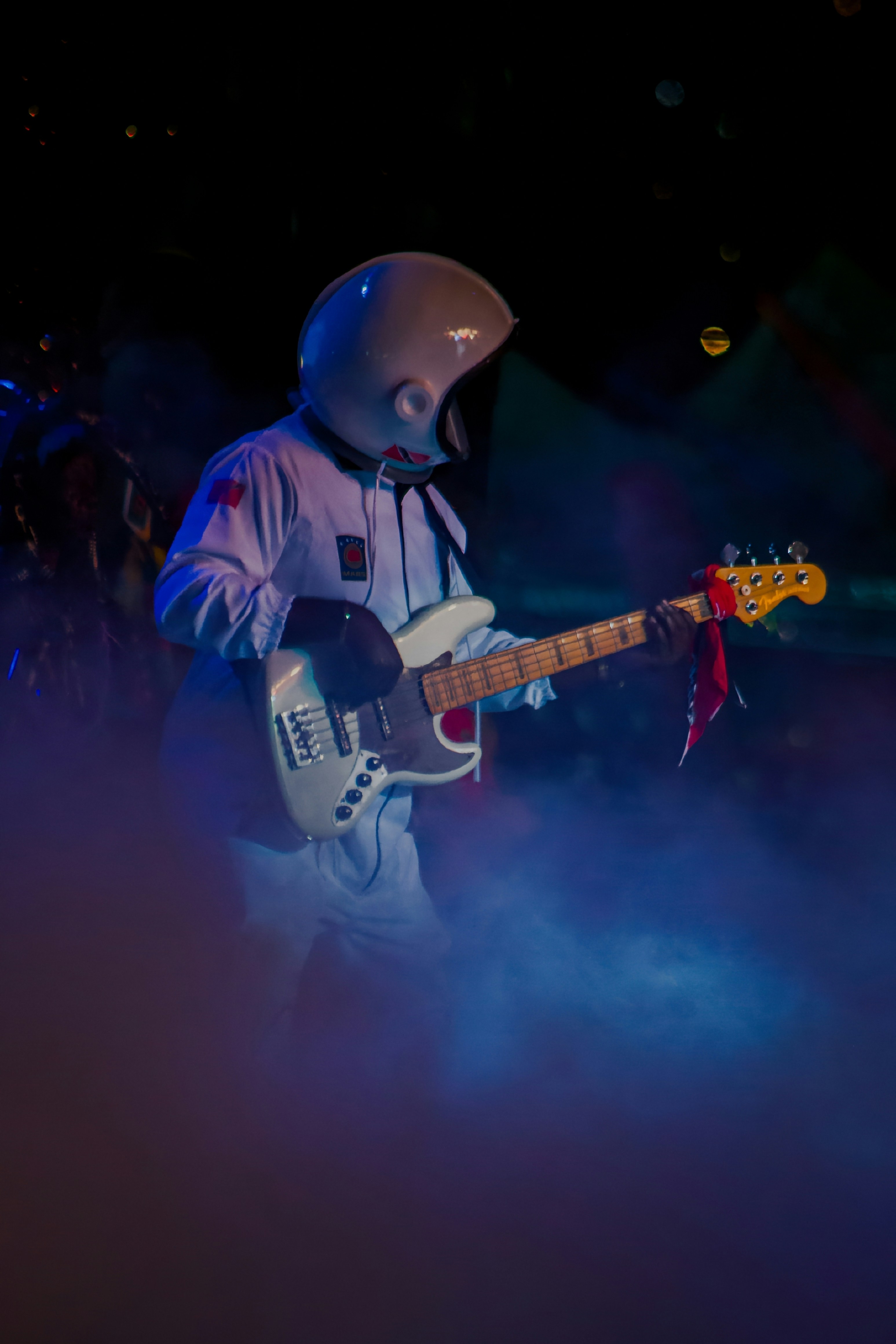Astronaut plays the bass guitar on stage.