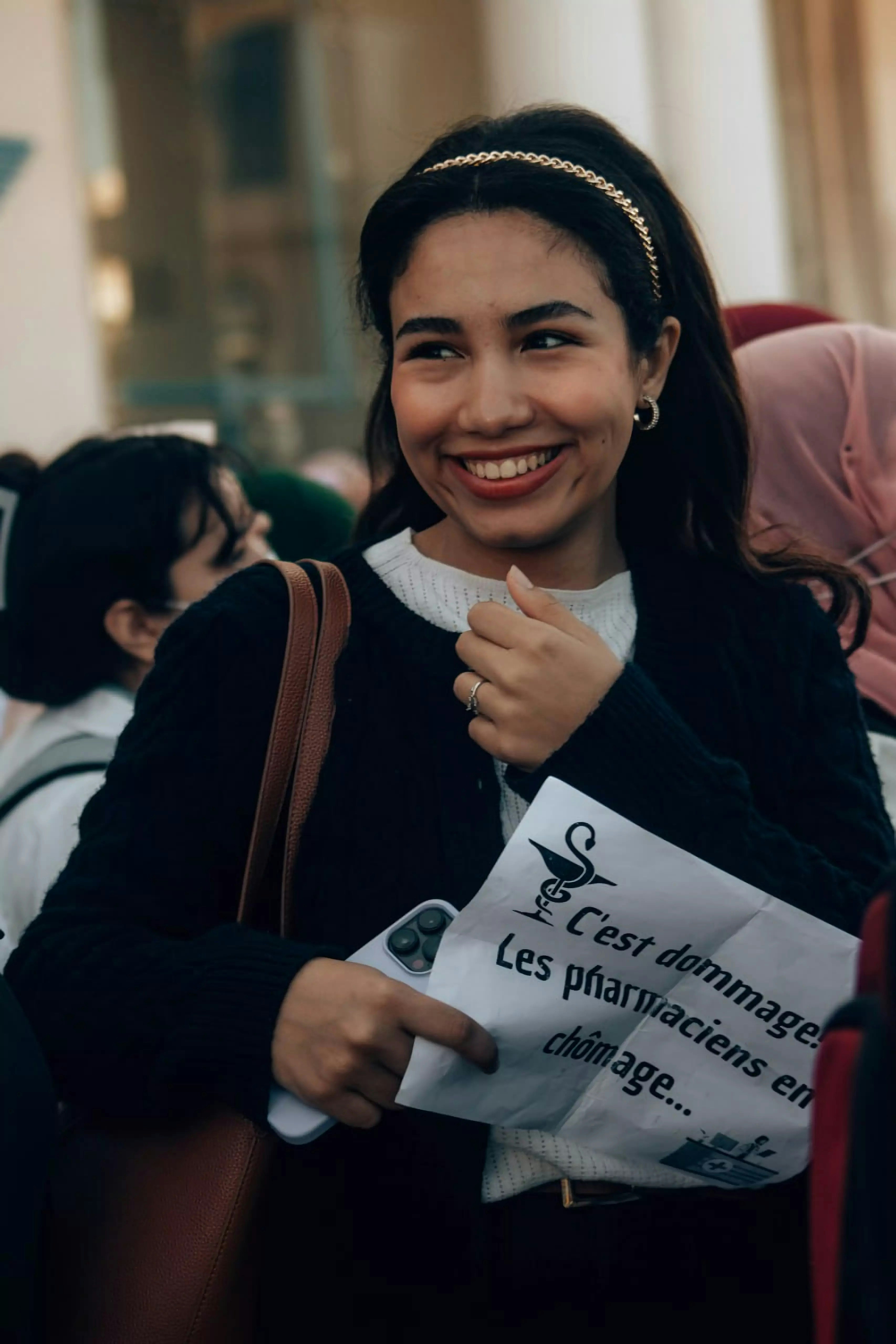 Smiling woman holds a sign with french text.