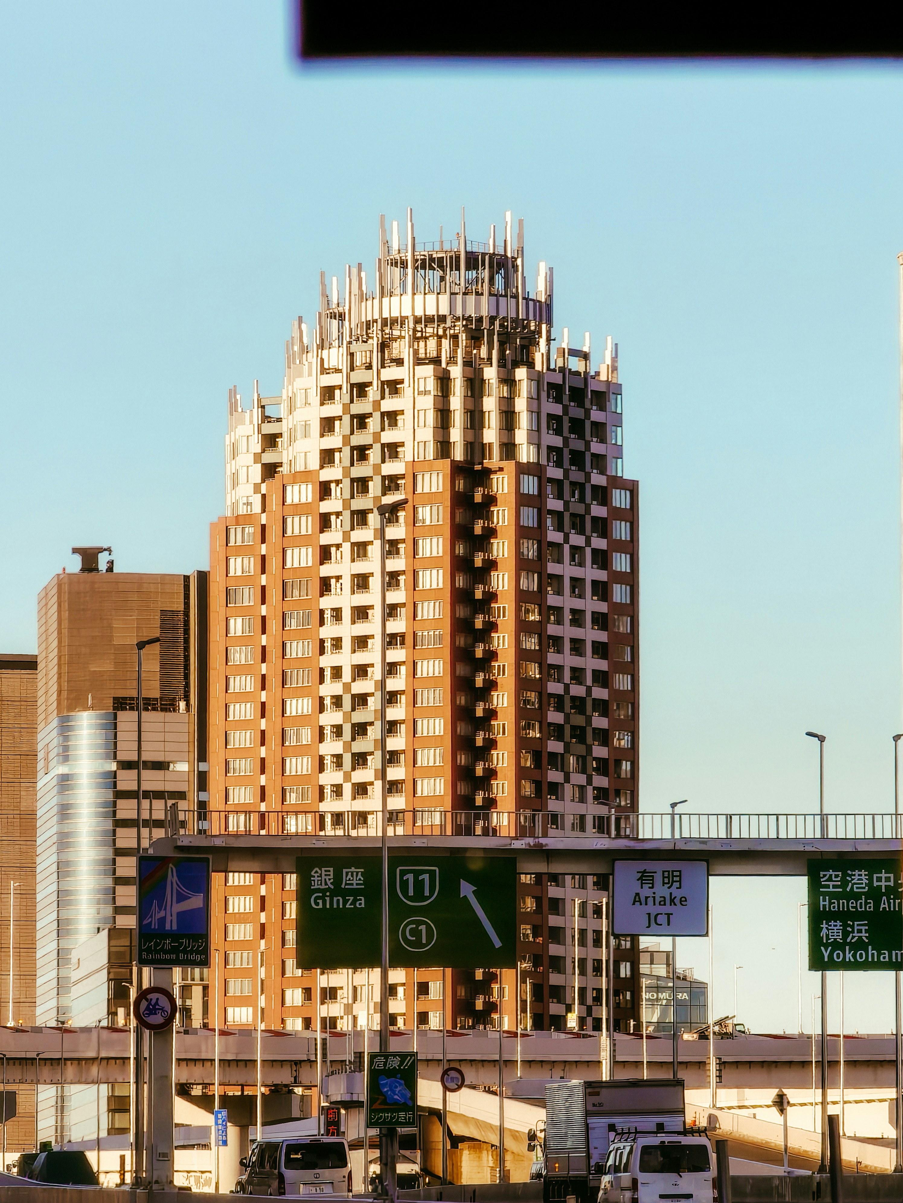 A tall building stands over busy road signs.