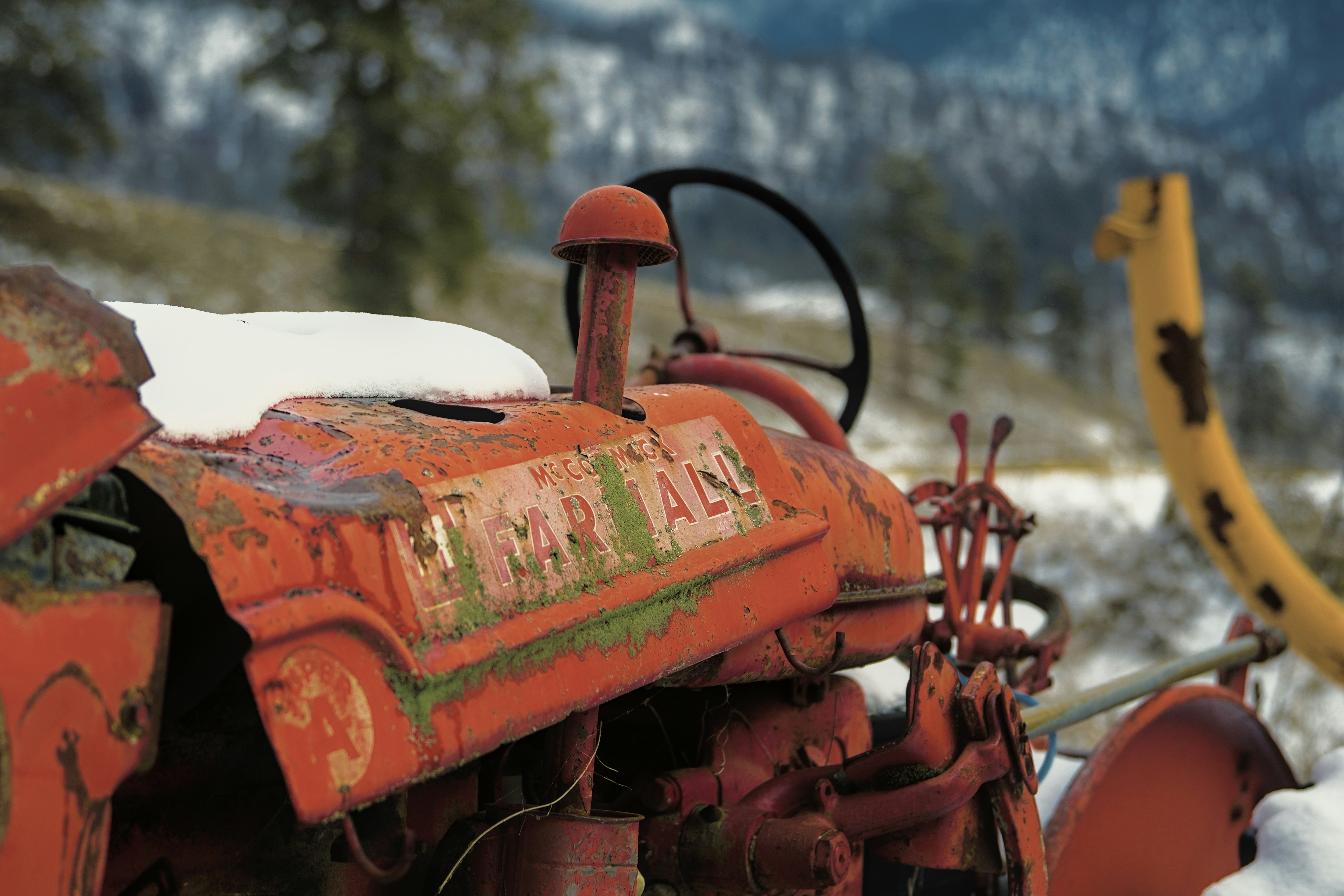 An old, rusty tractor stands in the snow.