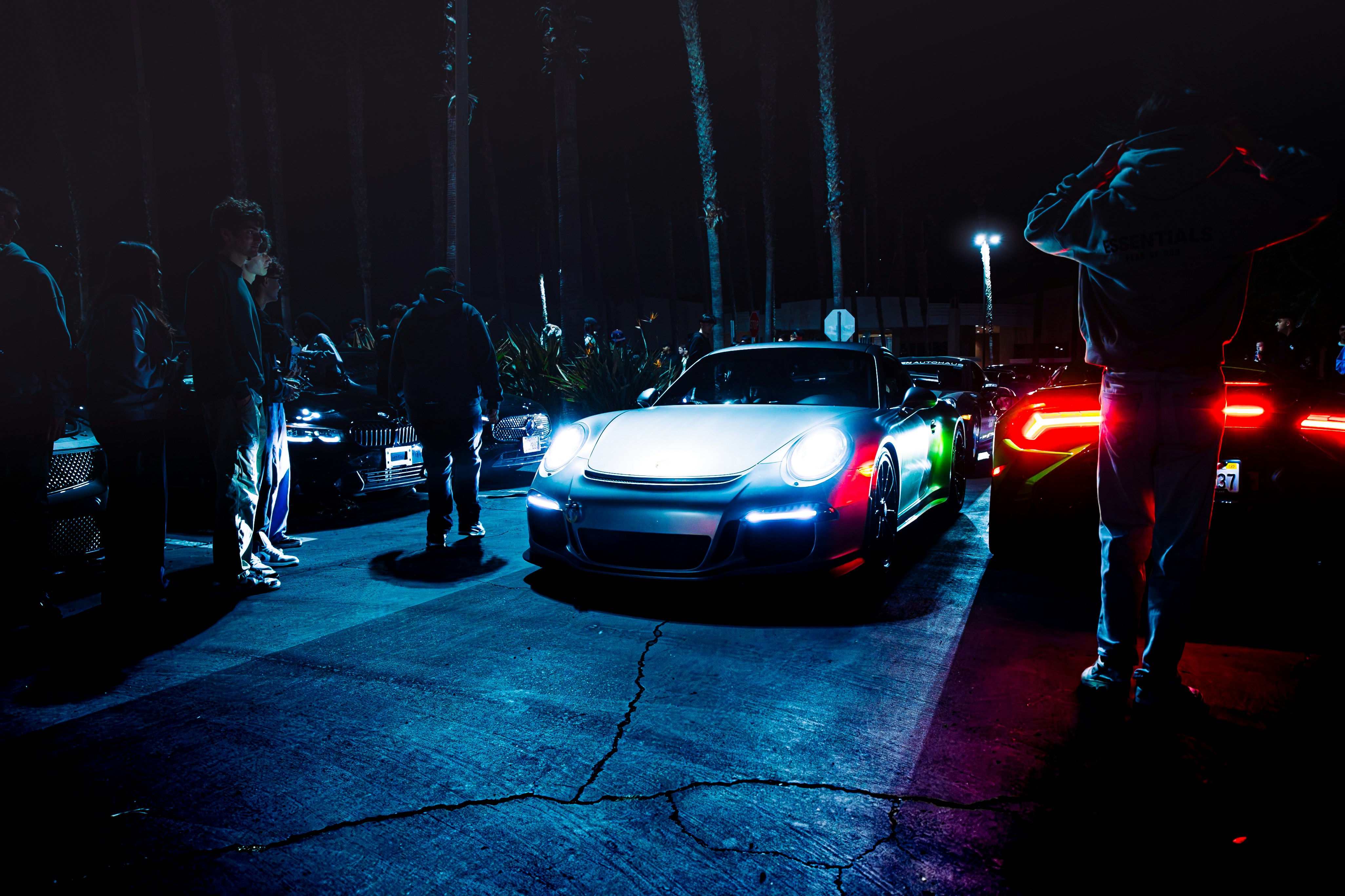 Cars and people gather on a dark street.