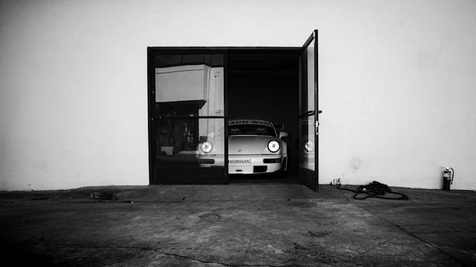 Car partially inside an open, dark garage door.