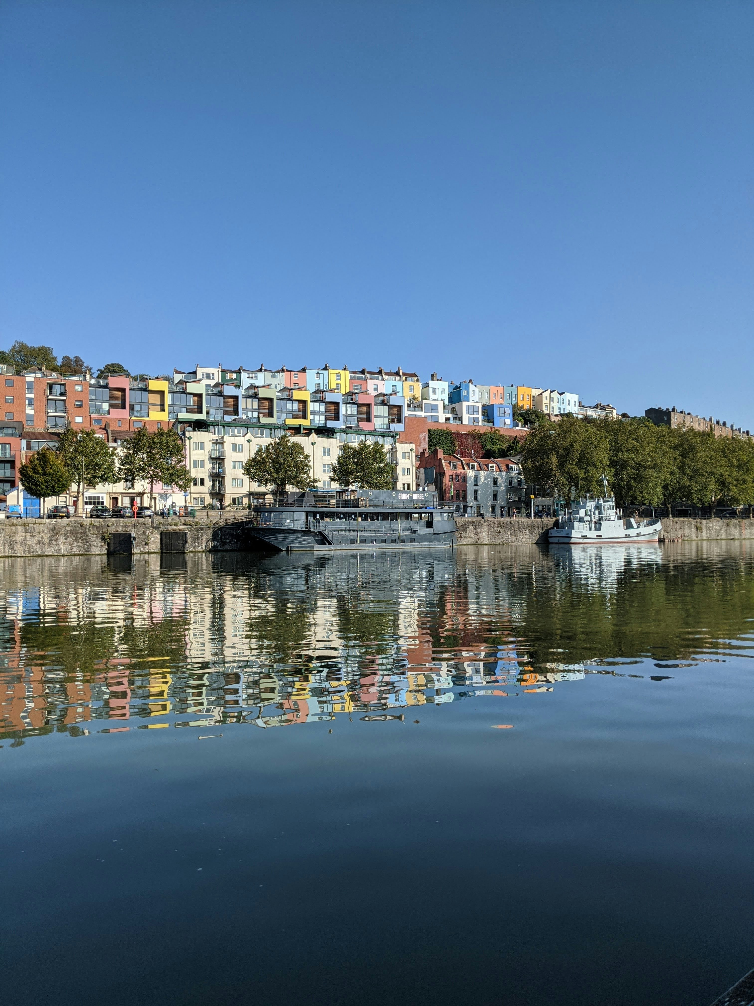 Colorful buildings reflect in calm water.