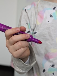 A child holds a purple marker.