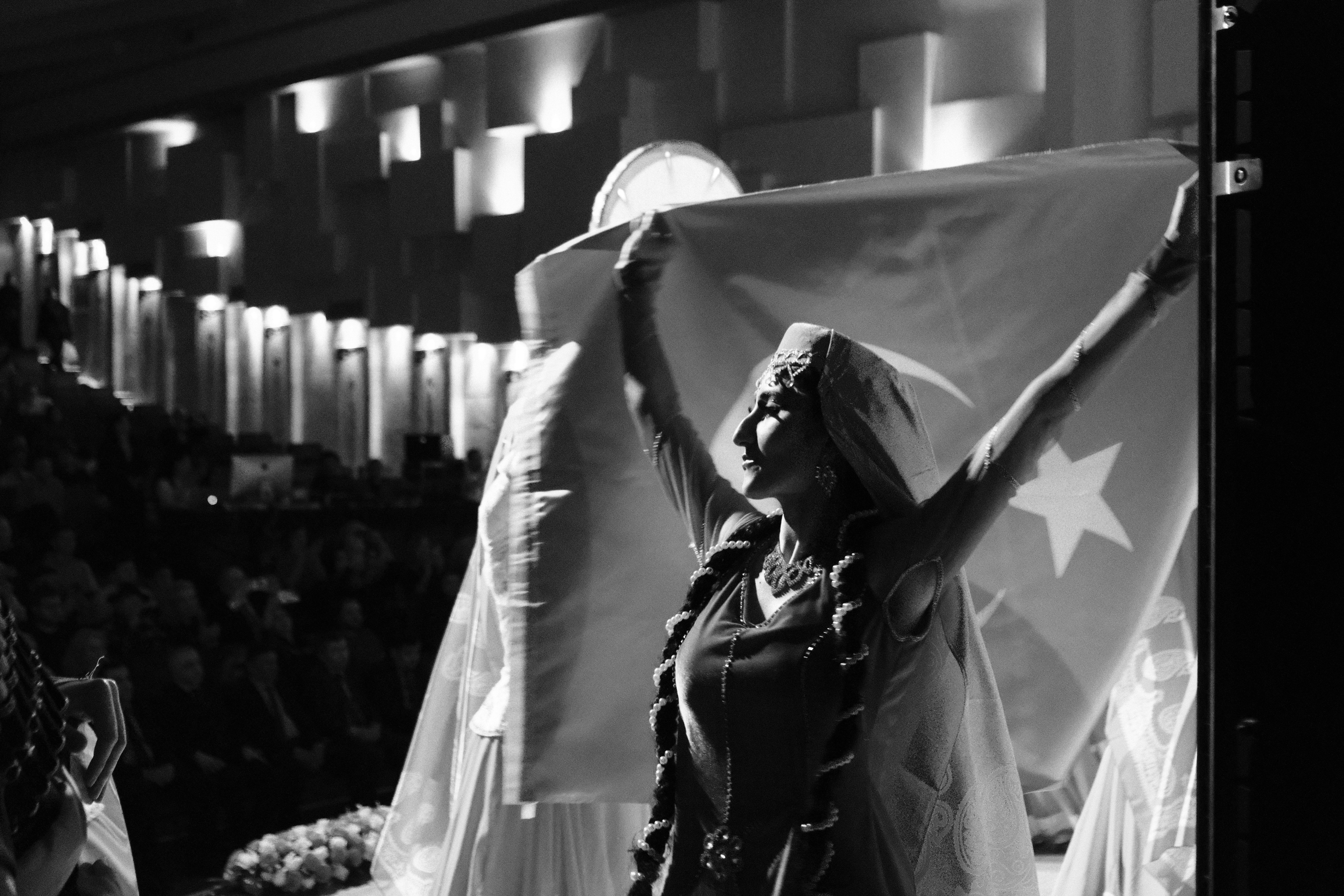 A woman raises a flag on a stage.