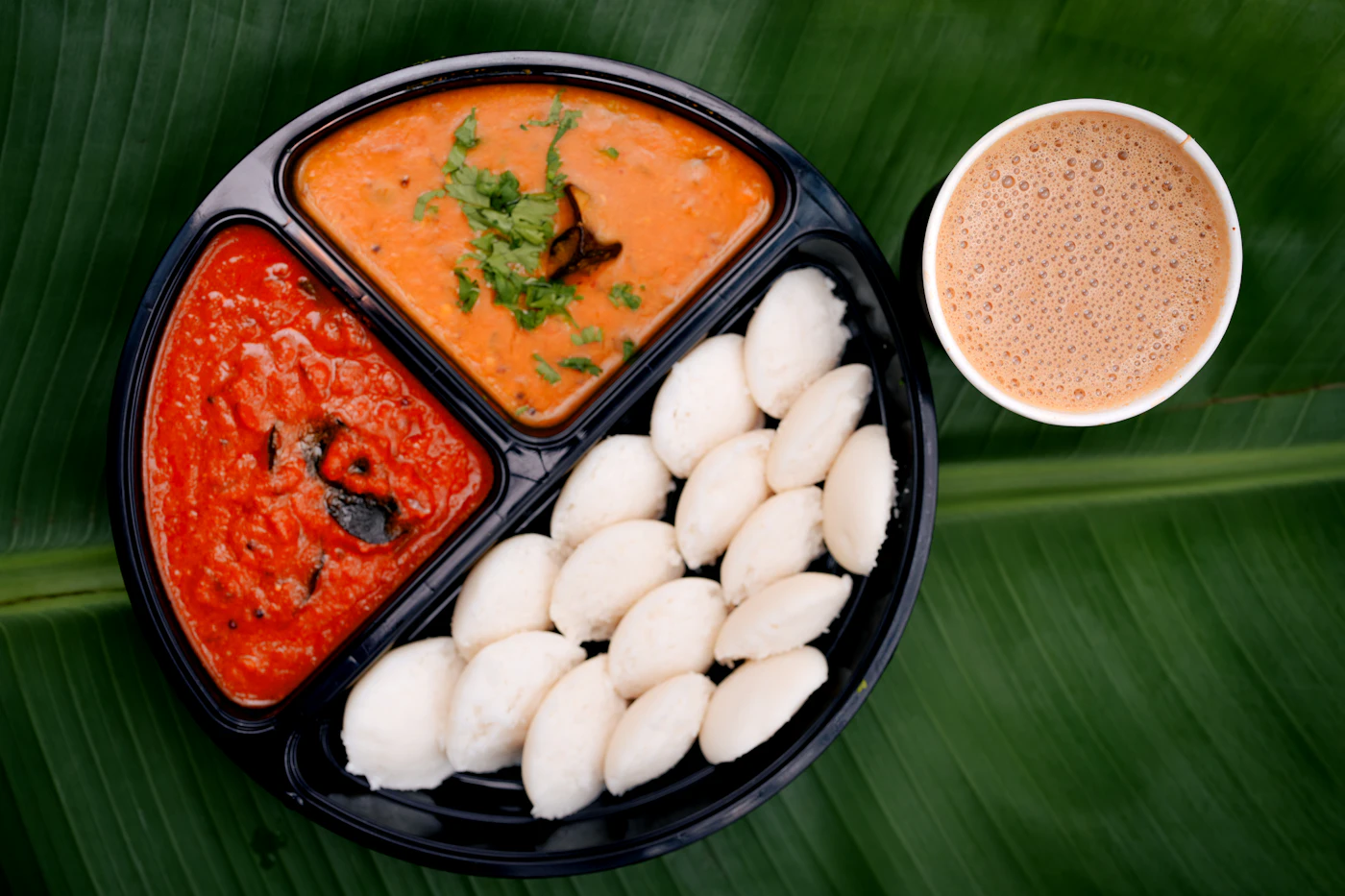 Idli served with sambar, coconut chutney and filter coffee on a South Indian breakfast plate