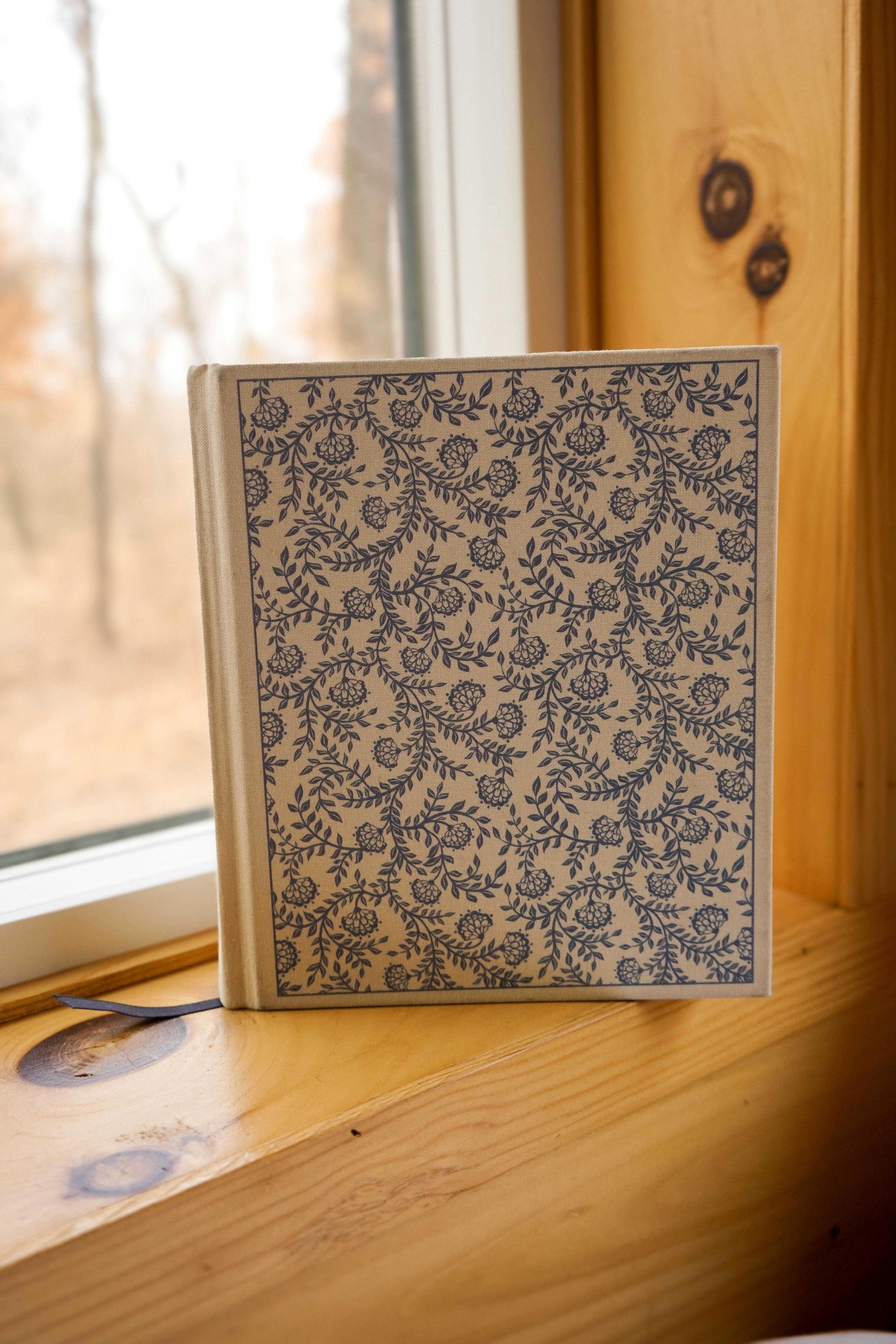A patterned book sits on a wooden windowsill.