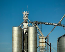 Grain silos stand tall against a clear blue sky.