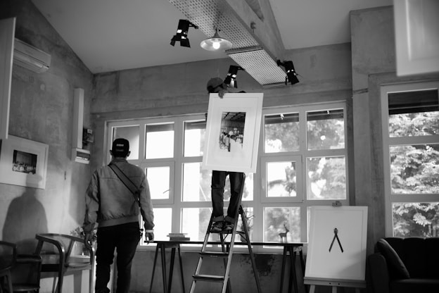 People are hanging artwork in an art gallery.