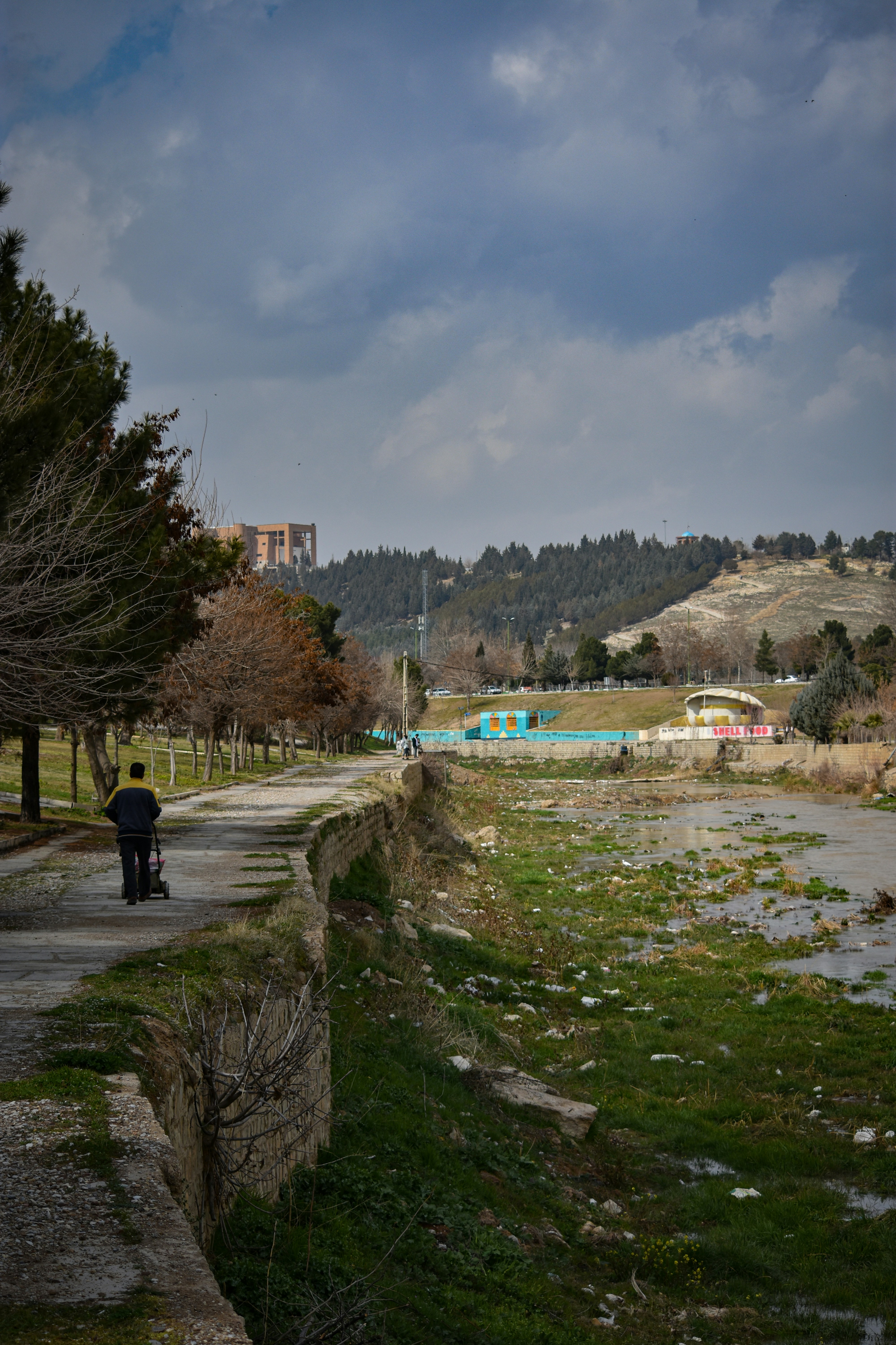 Um homem caminha por um caminho à beira de um rio.