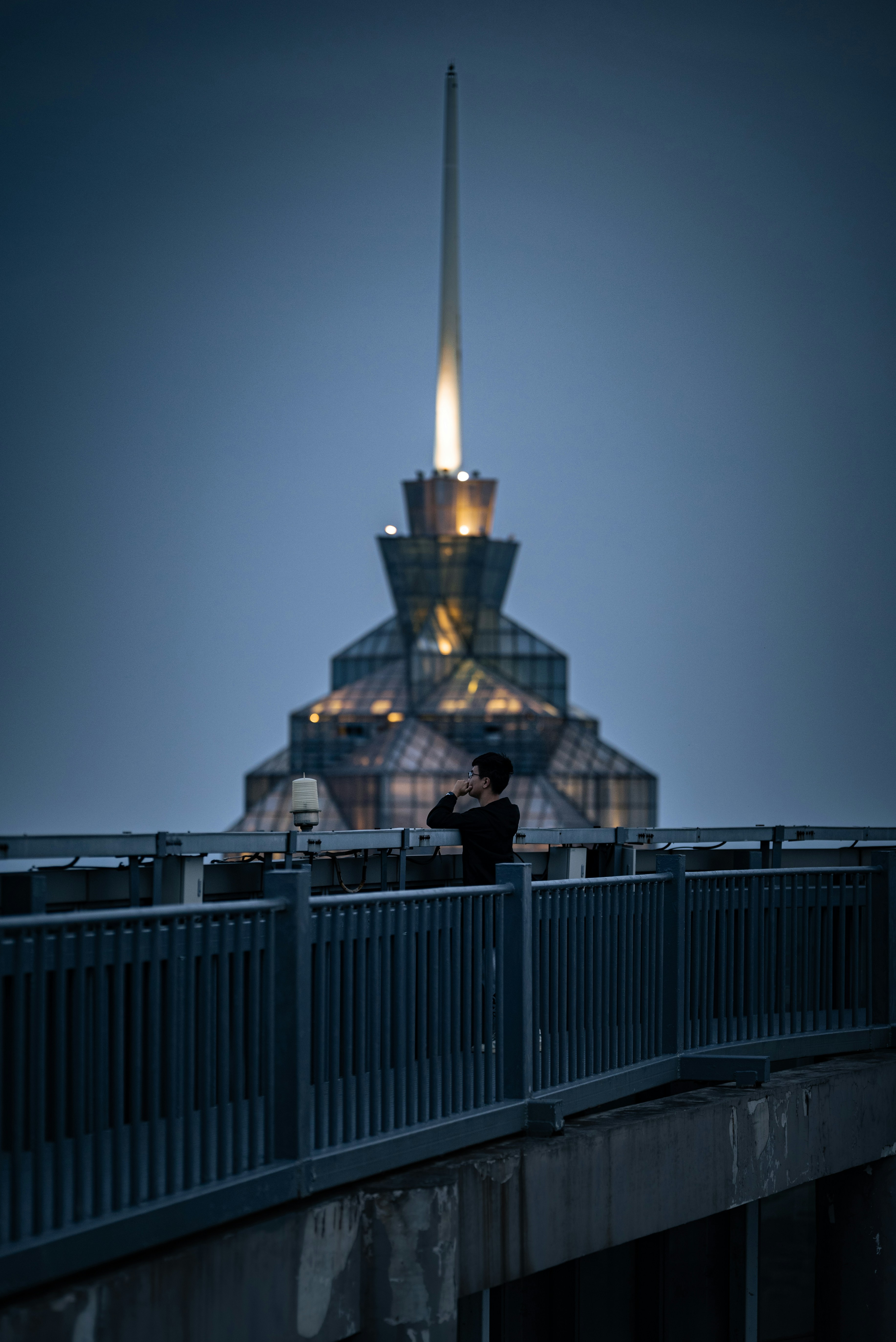 Man taking picture of a futuristic building at night.