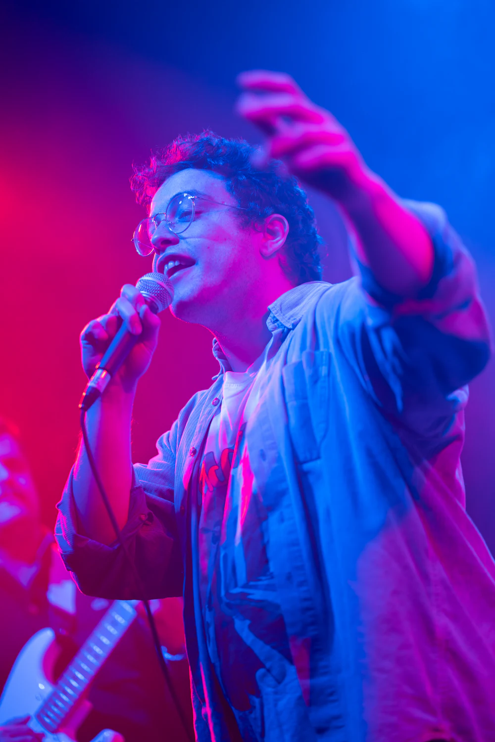 Cantante interpretando una canción bajo luces rojas y azules