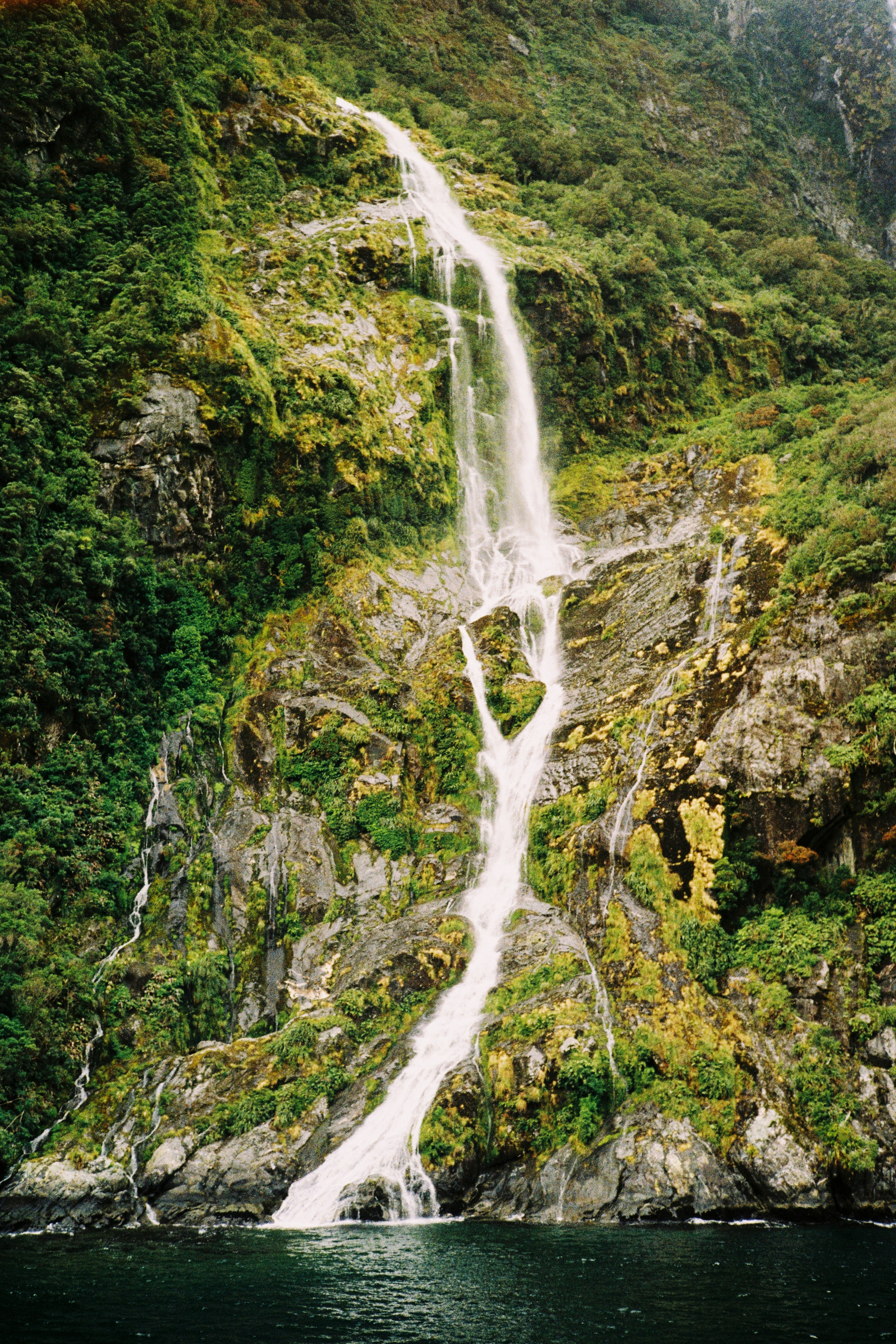 A waterfall cascades down a lush, rocky cliffside.