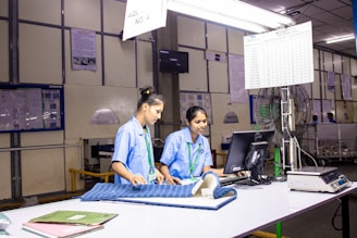 Two women work together at a factory workstation.