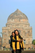 Mother and daughter smile in front of a monument.