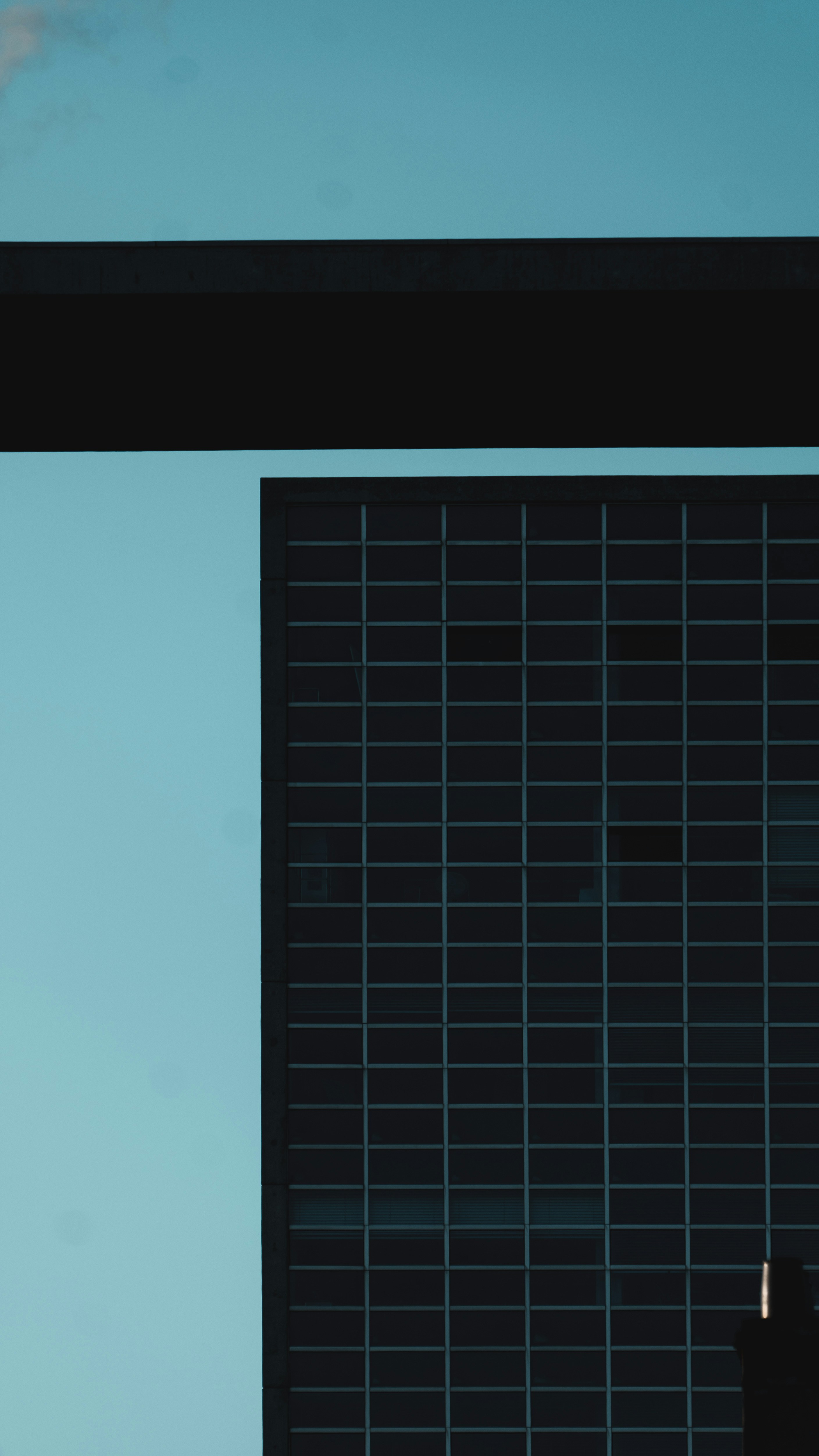 Building with grid-like facade beneath a dark beam.