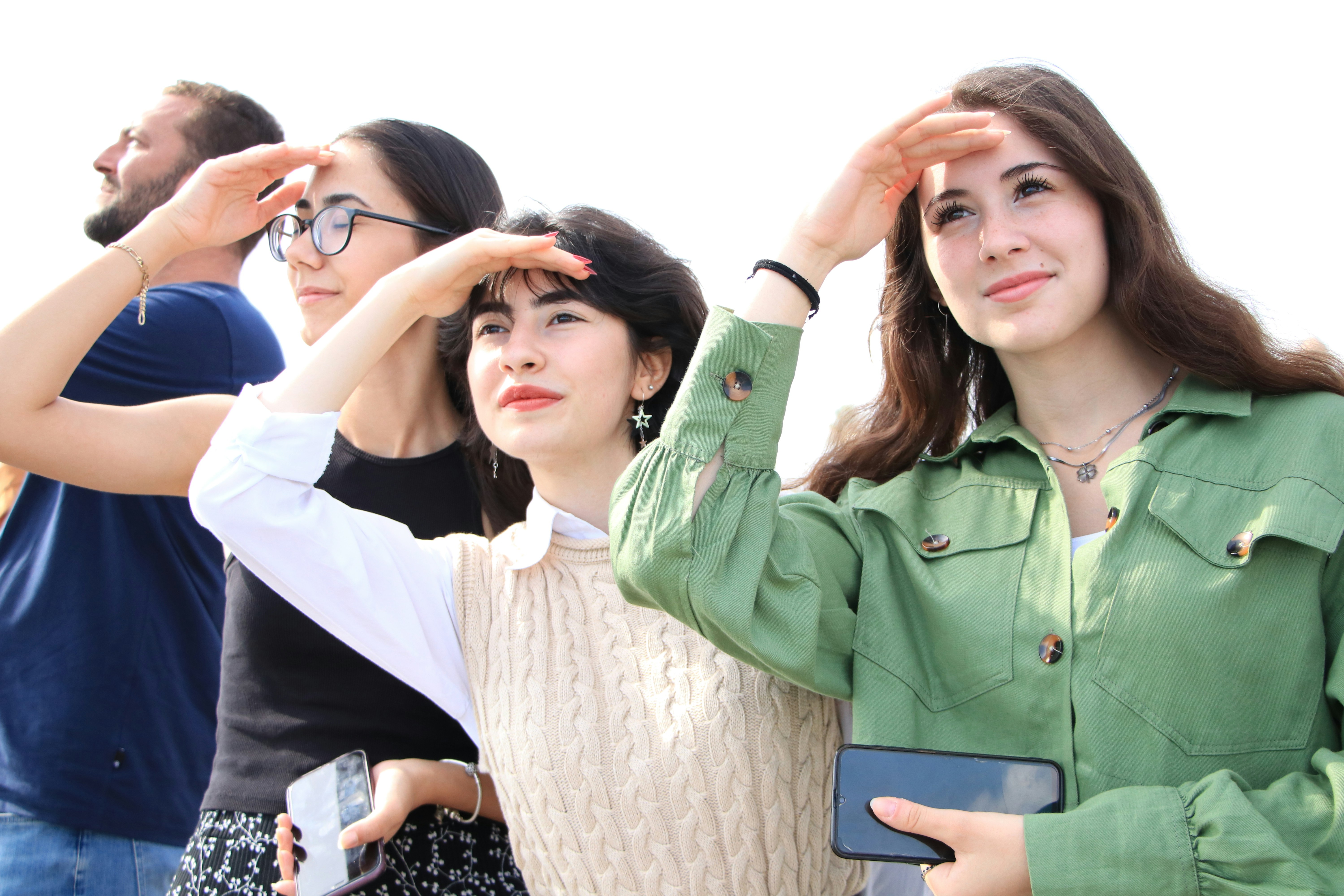 People looking off into the distance, shading their eyes.