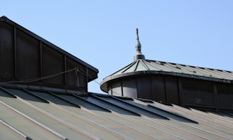 Rooftops with a stylish spire against a blue sky.