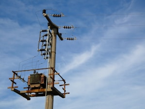 Power lines and a transformer against a blue sky.