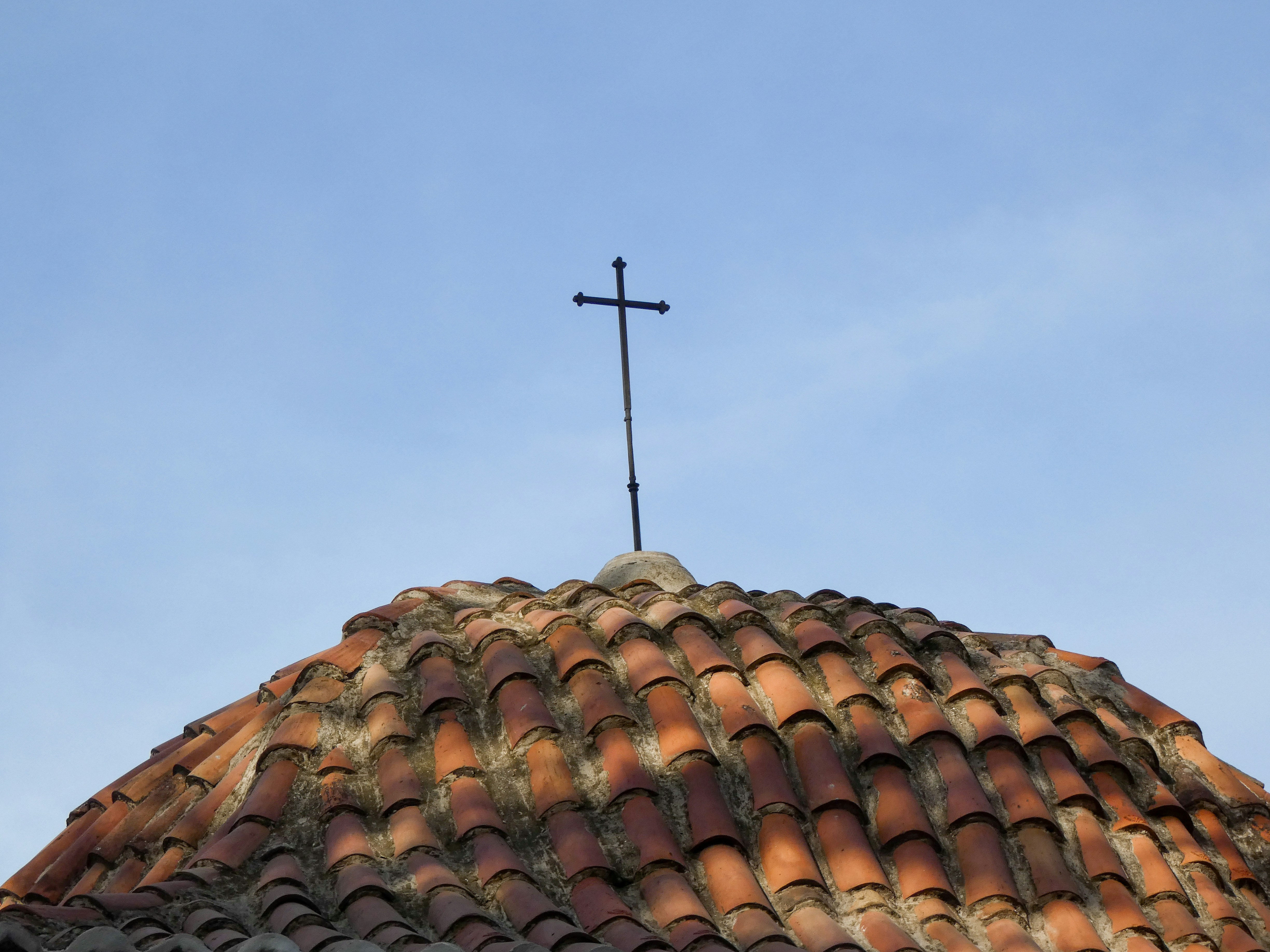 A cross rests upon a rooftop.