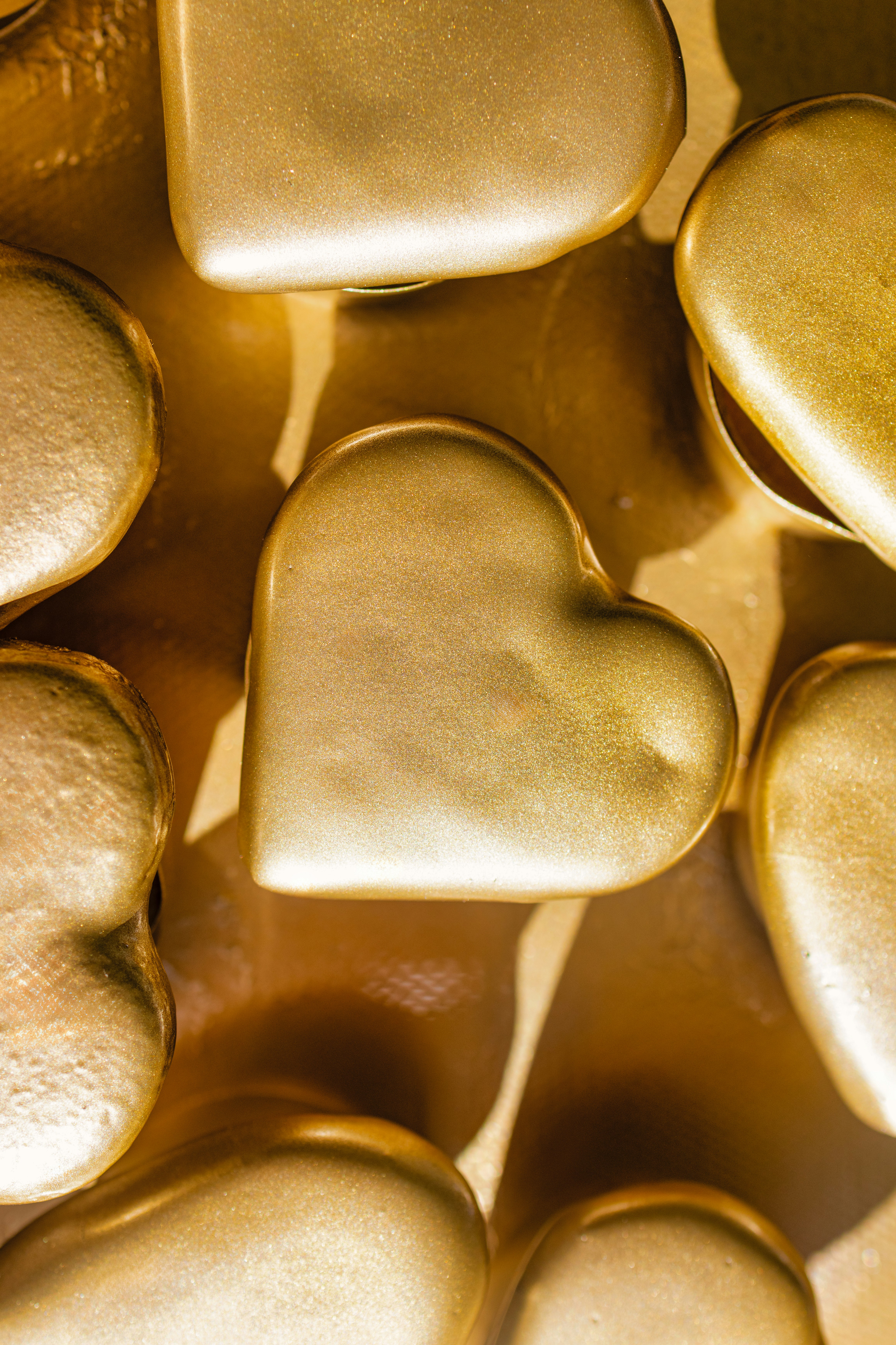 Golden hearts are arranged close together on a surface
