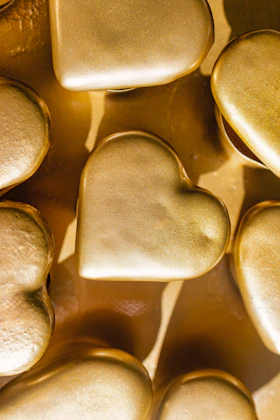 Golden hearts are arranged close together on a surface.
