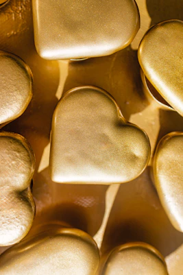 Golden hearts are arranged close together on a surface.