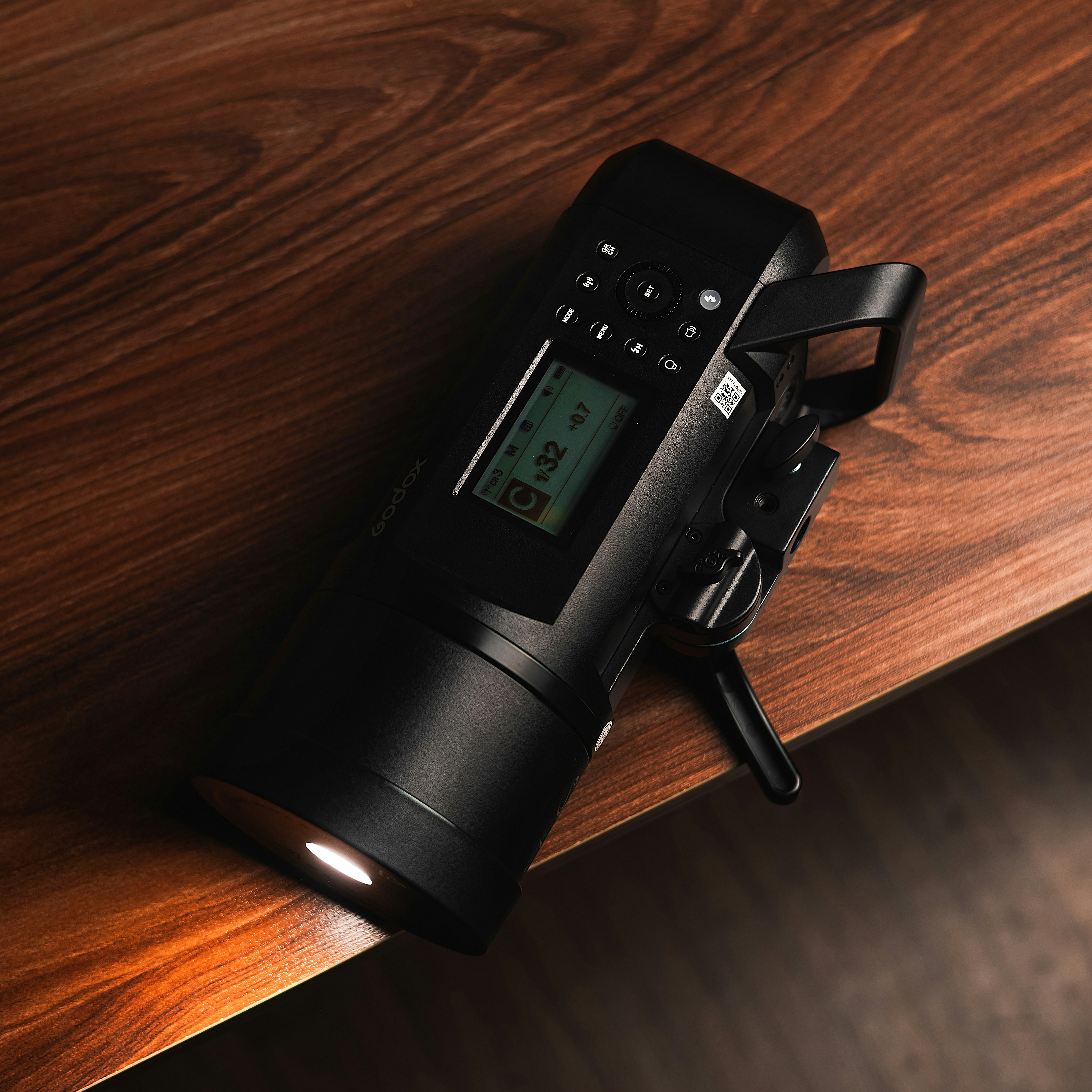 A flashlight is illuminated on a wooden surface.