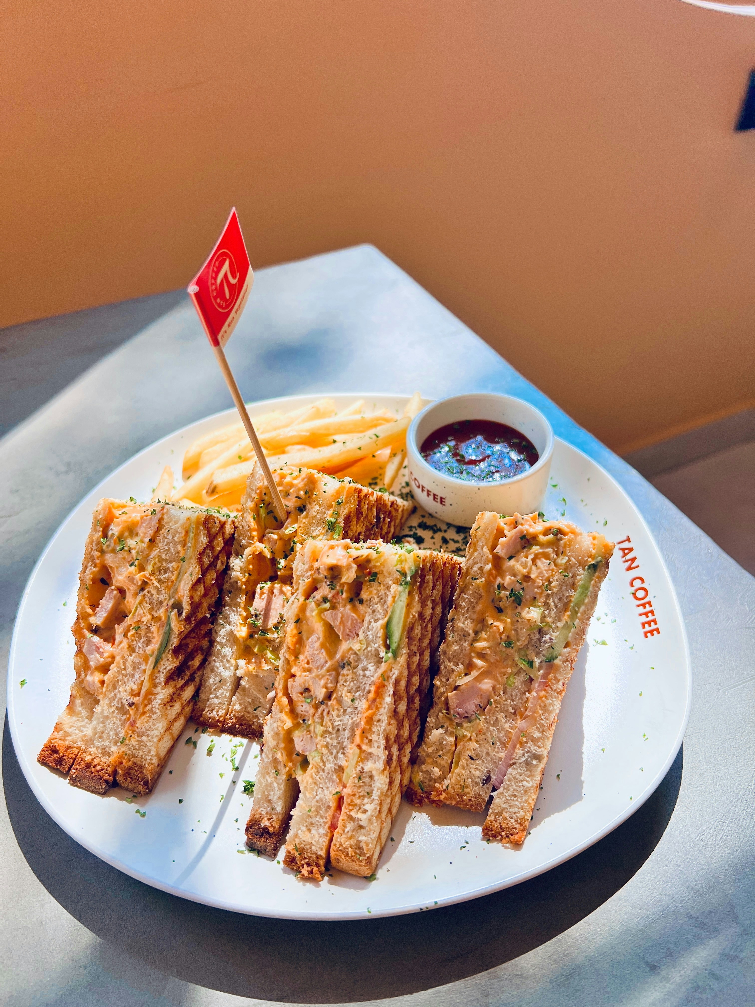 Sandwich panggang, kentang goreng, dan saus ditampilkan.