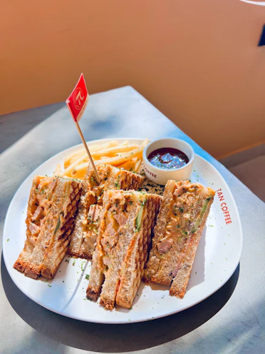 Grilled sandwiches, fries, and sauce are displayed.