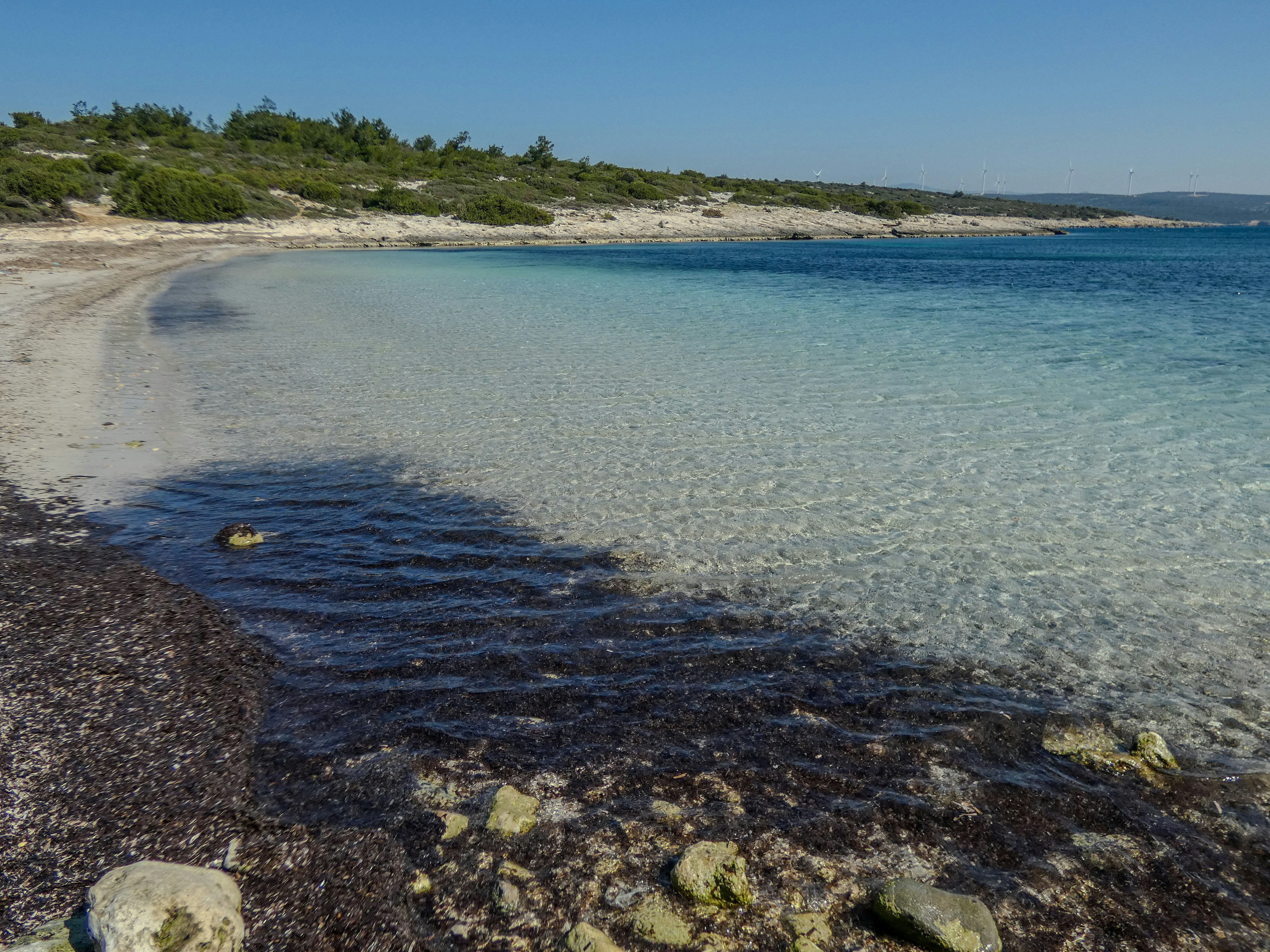 A clear, turquoise ocean meets a rocky coast.