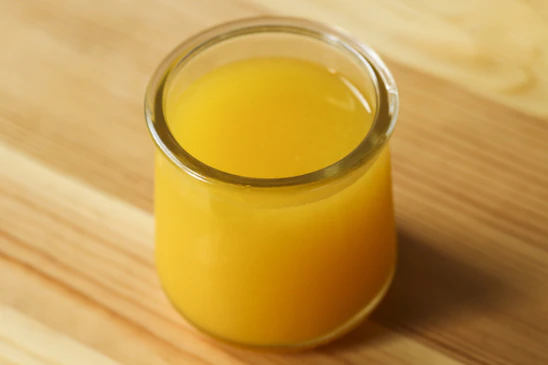 A glass of orange juice sits on a table.