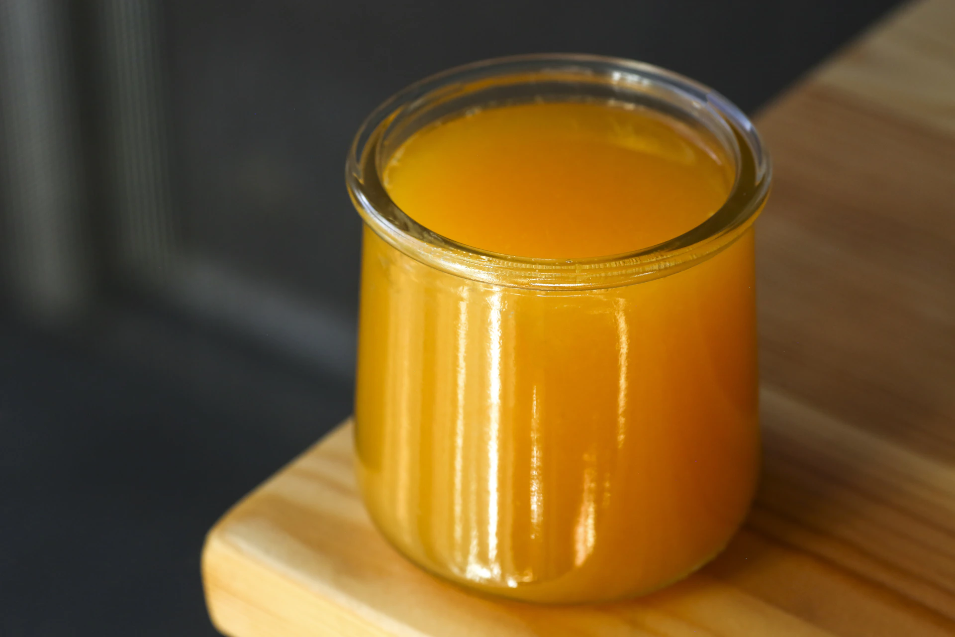 A glass of orange juice on wood.