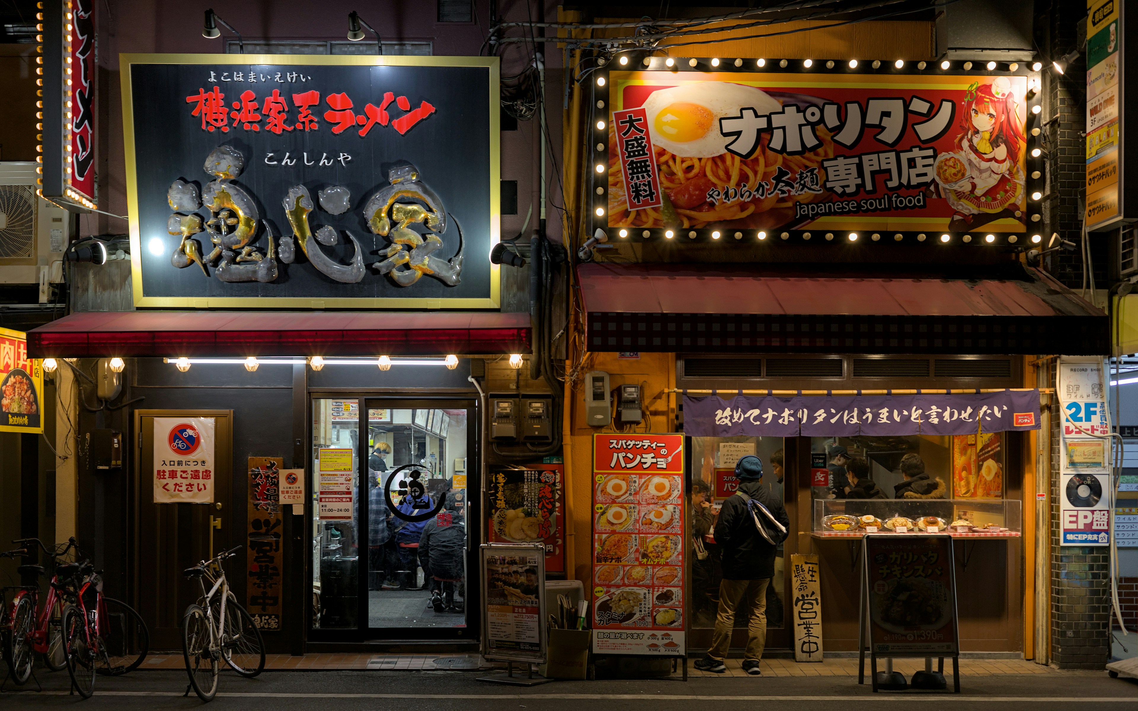 Two japanese restaurants glowing at night.