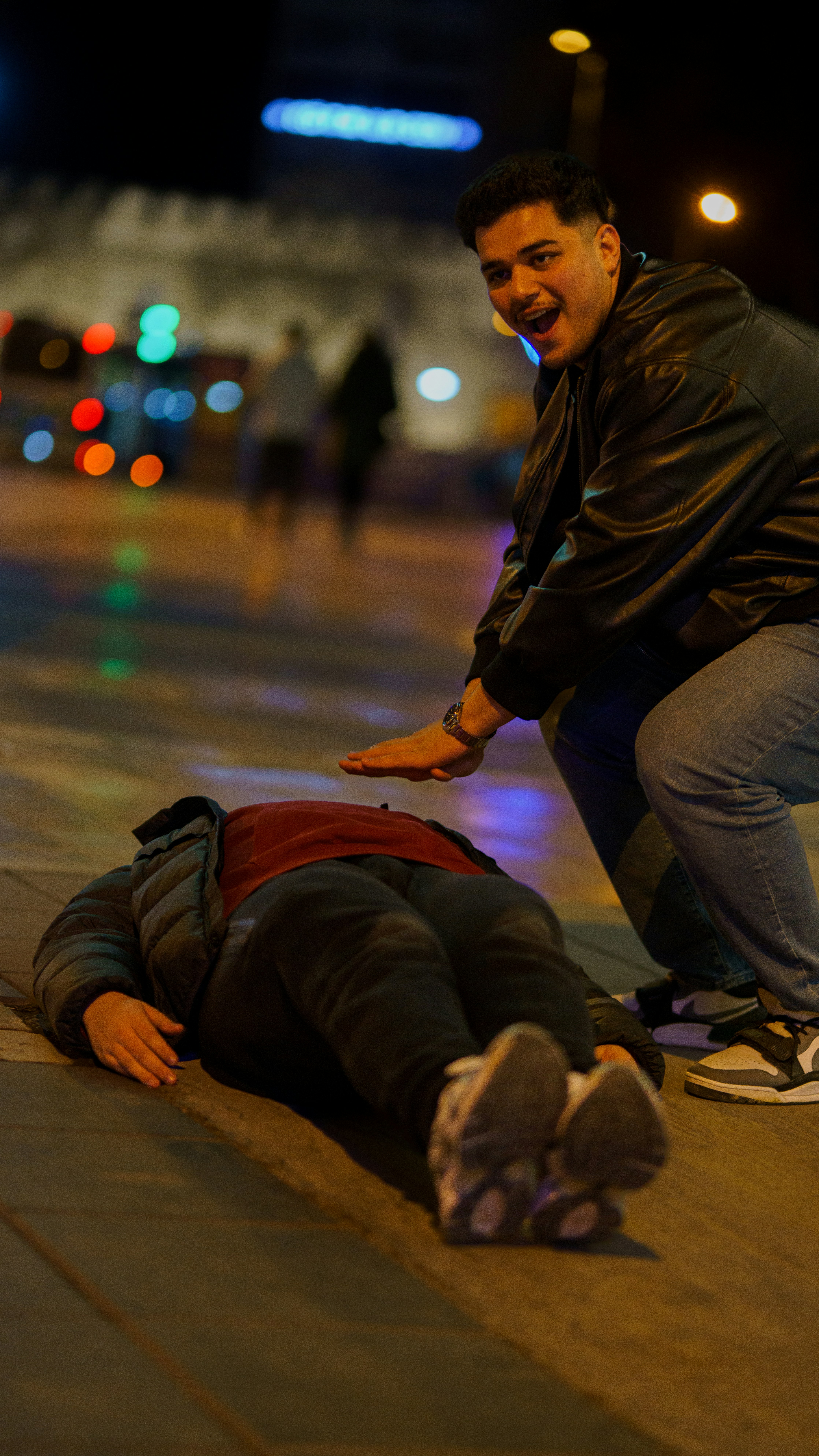 A person is lying on the ground as another looks down