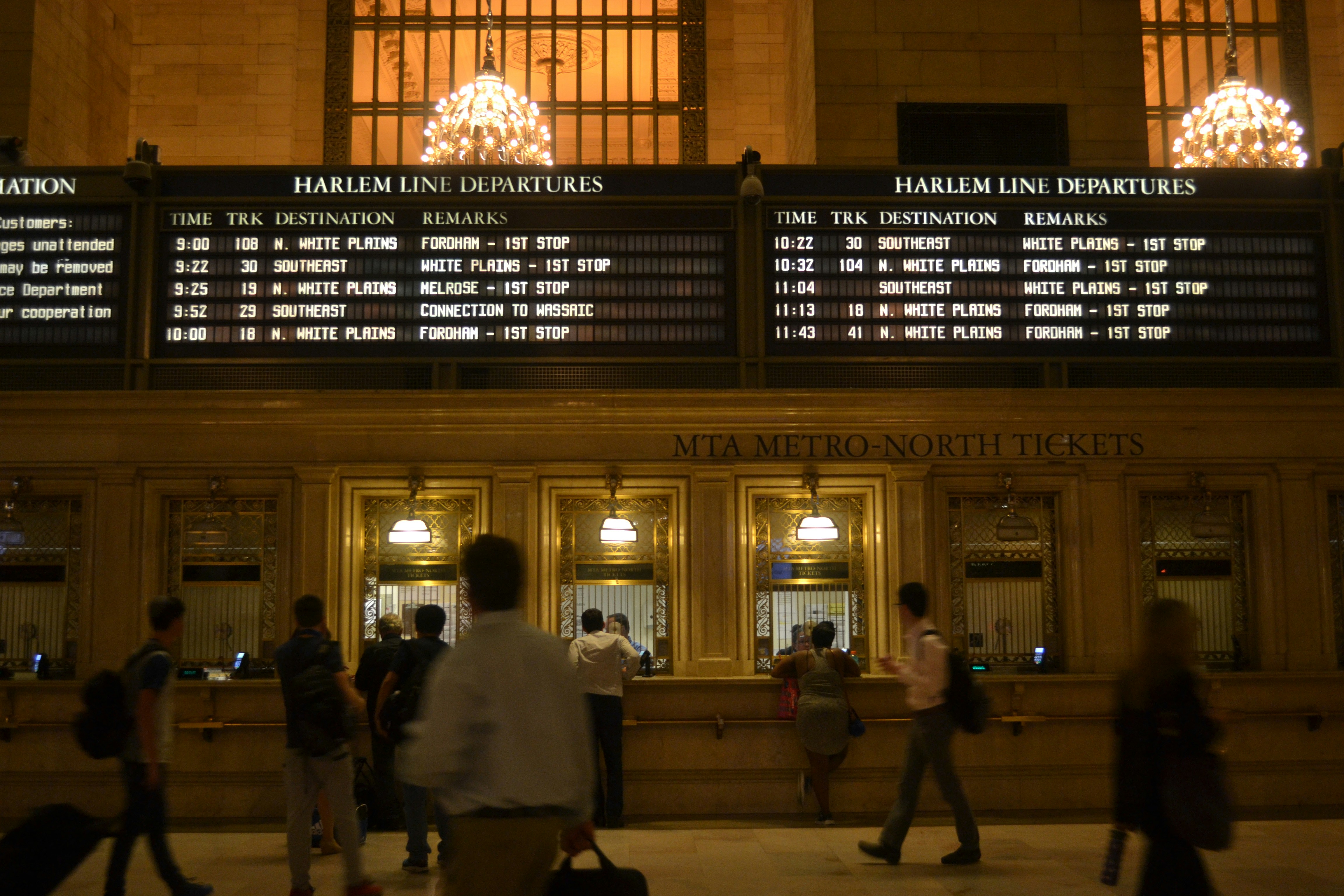 People are in a train station looking at departures.