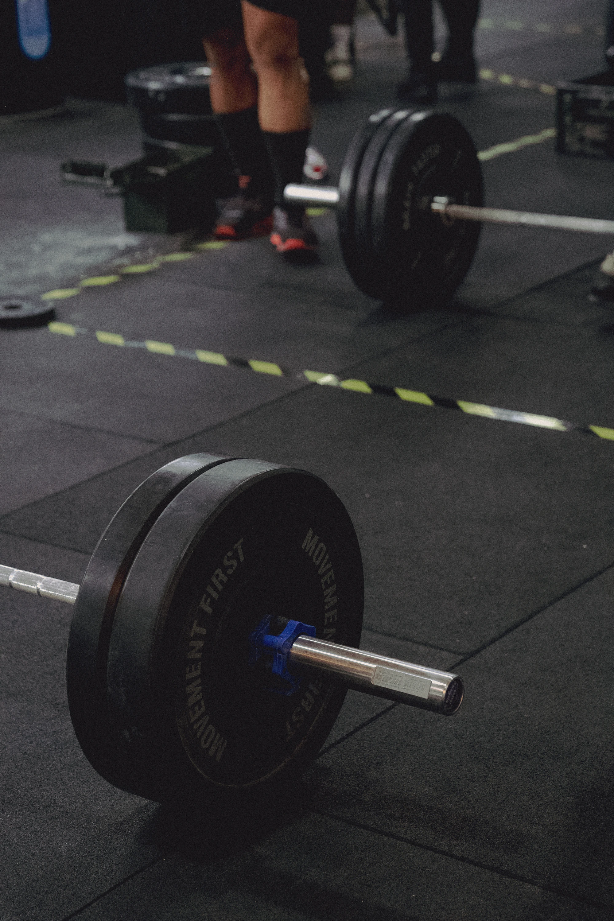 Olympic weightlifting barbell and bumper plates arranged in a real gym training area