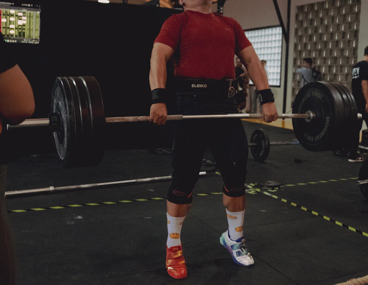 A lifter mid-pull under a loaded barbell in a training hall