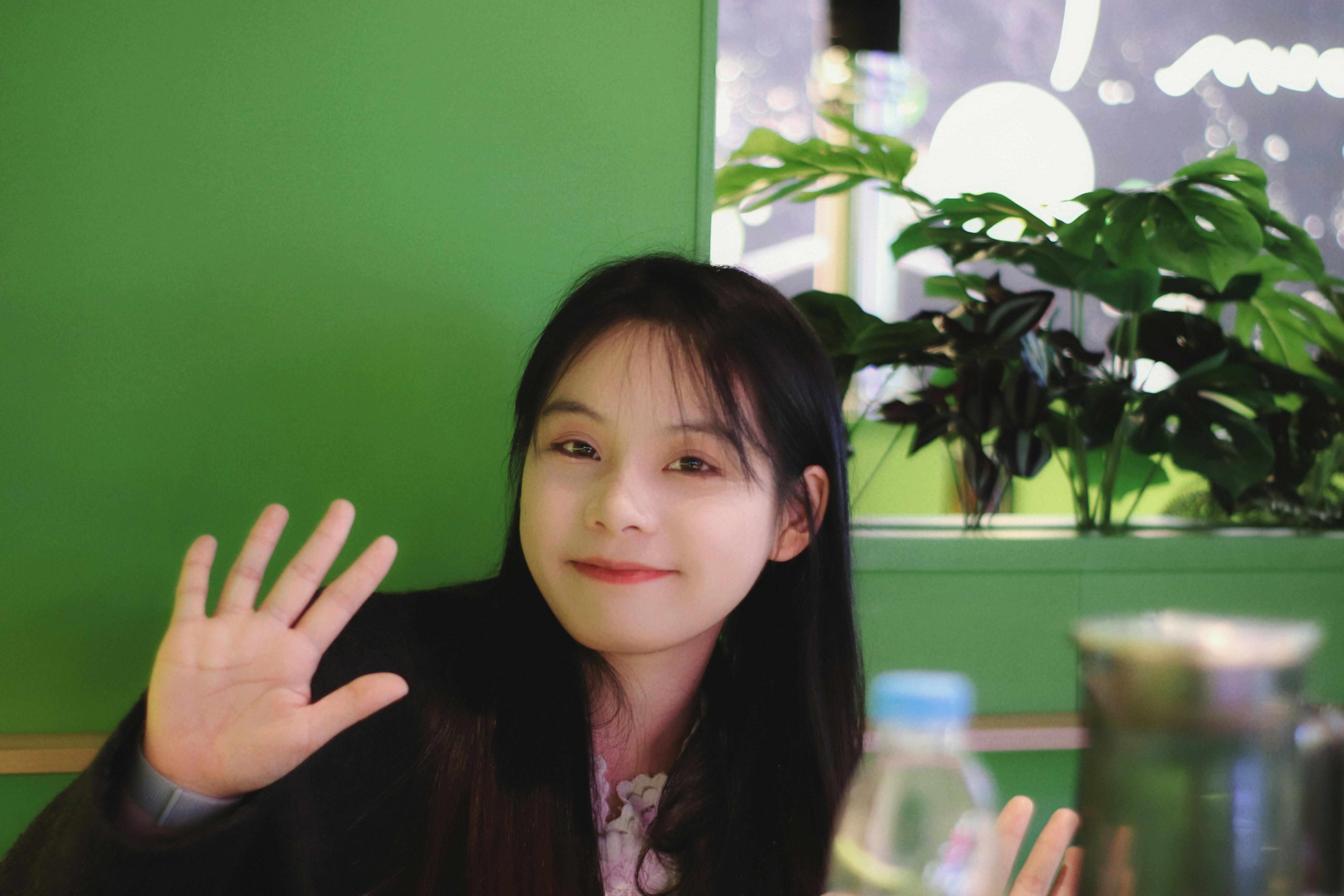 A young woman waving at the camera.