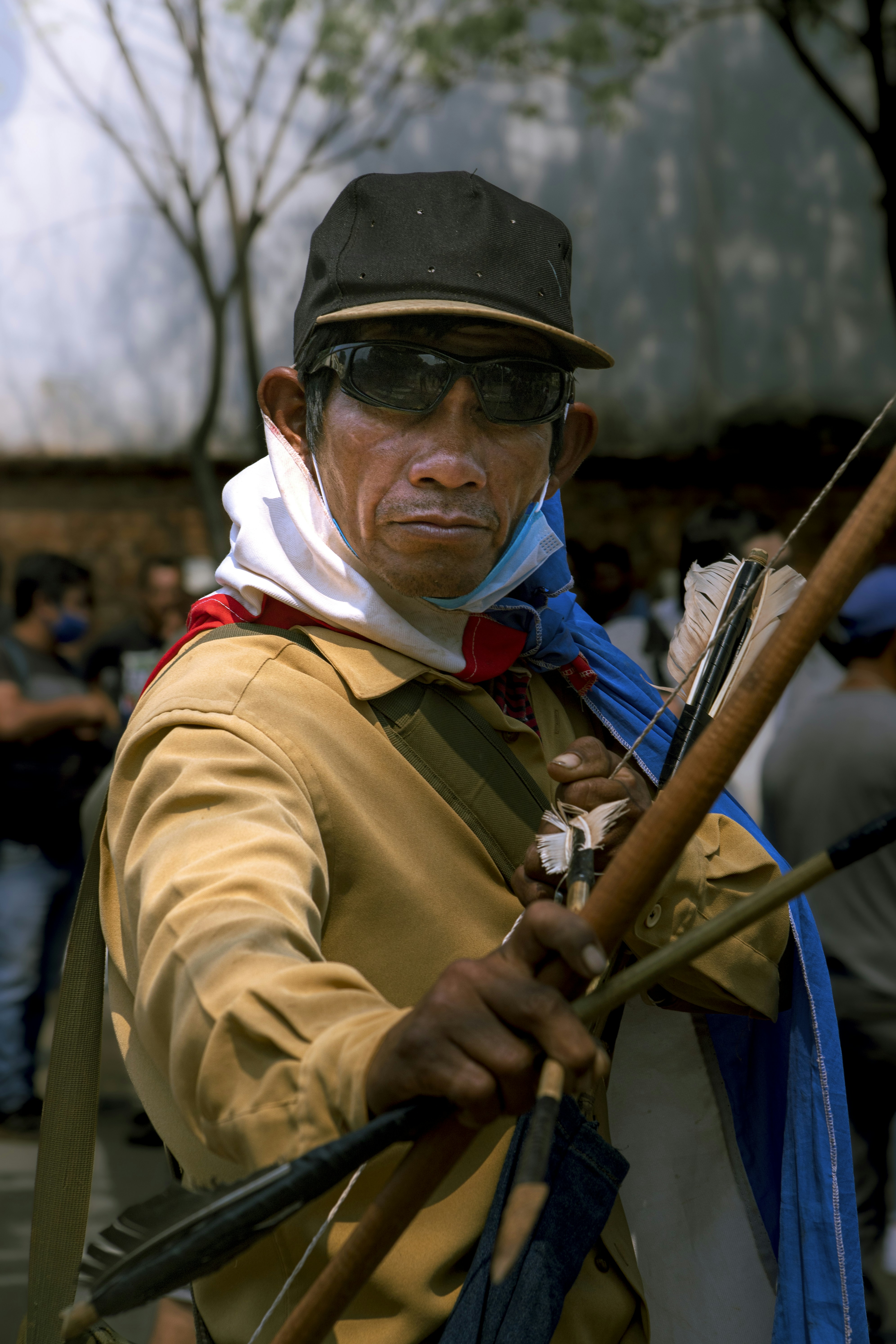 Man in traditional clothing holds a bow and arrow.