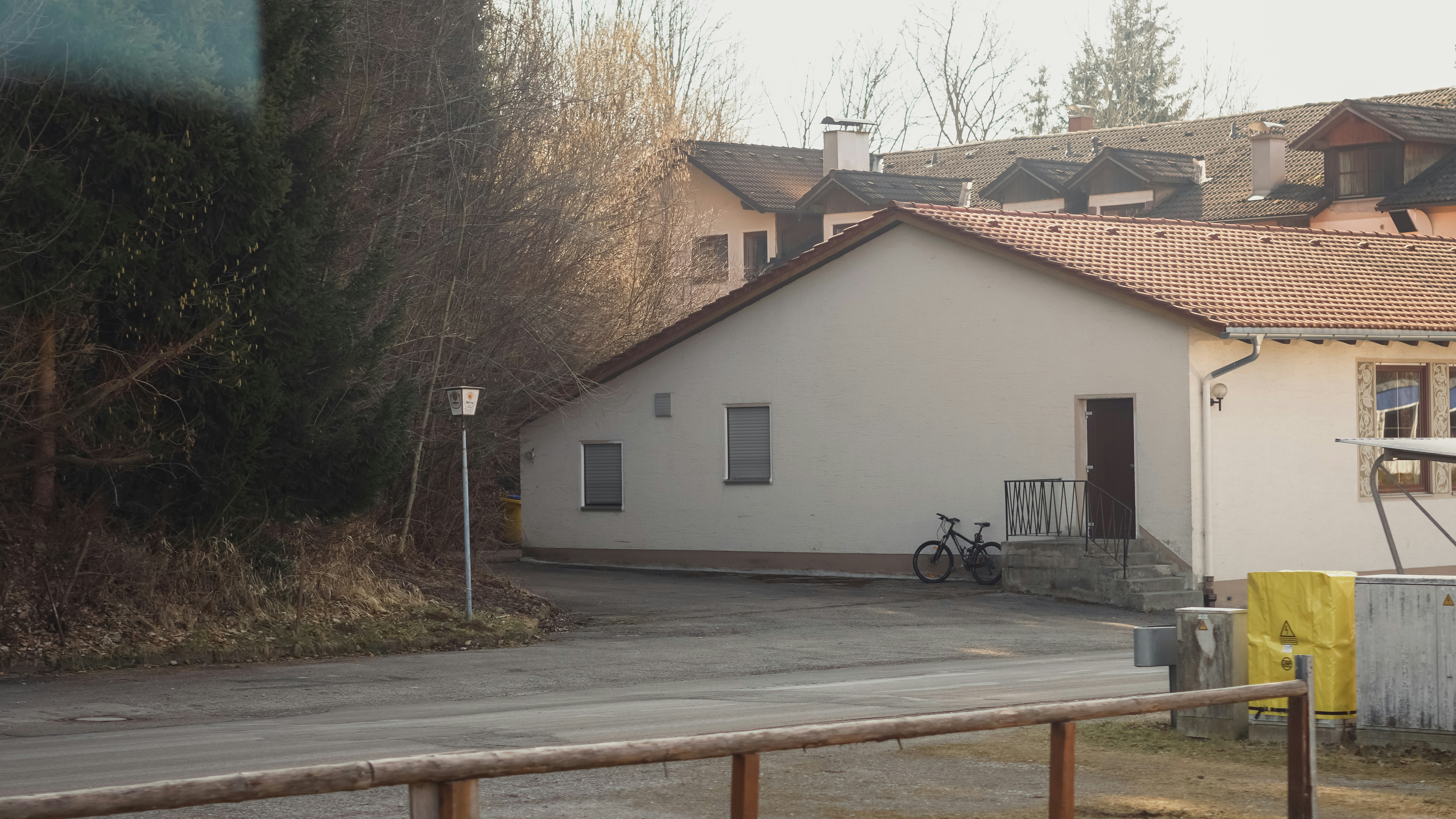 Buildings sit along a road near a forest.