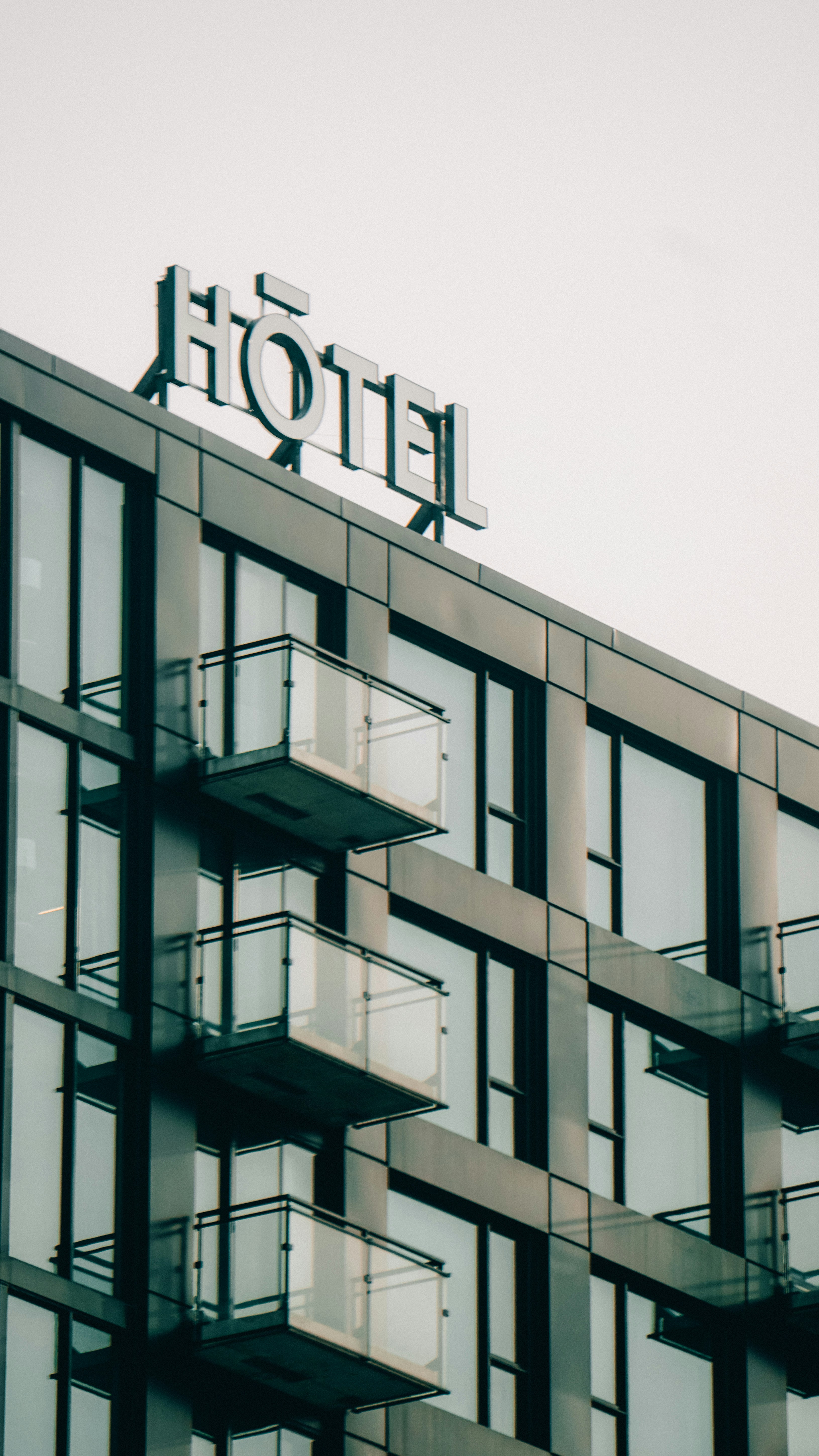 Modernes Hoteläußeres mit Balkon und Schild.
