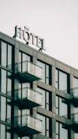 Modern hotel exterior with balconies and a sign.