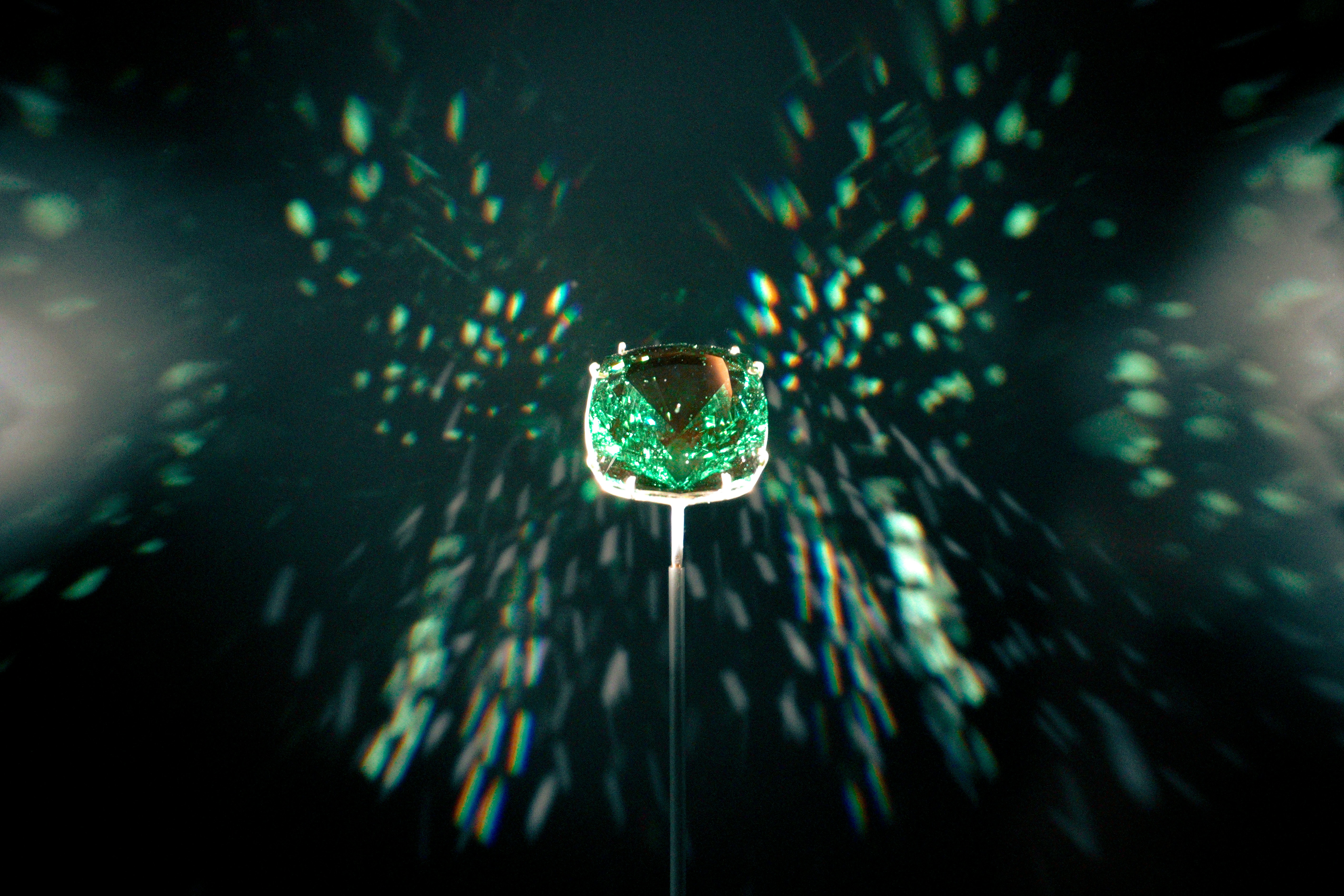 A green gem is showcased with a dark background.