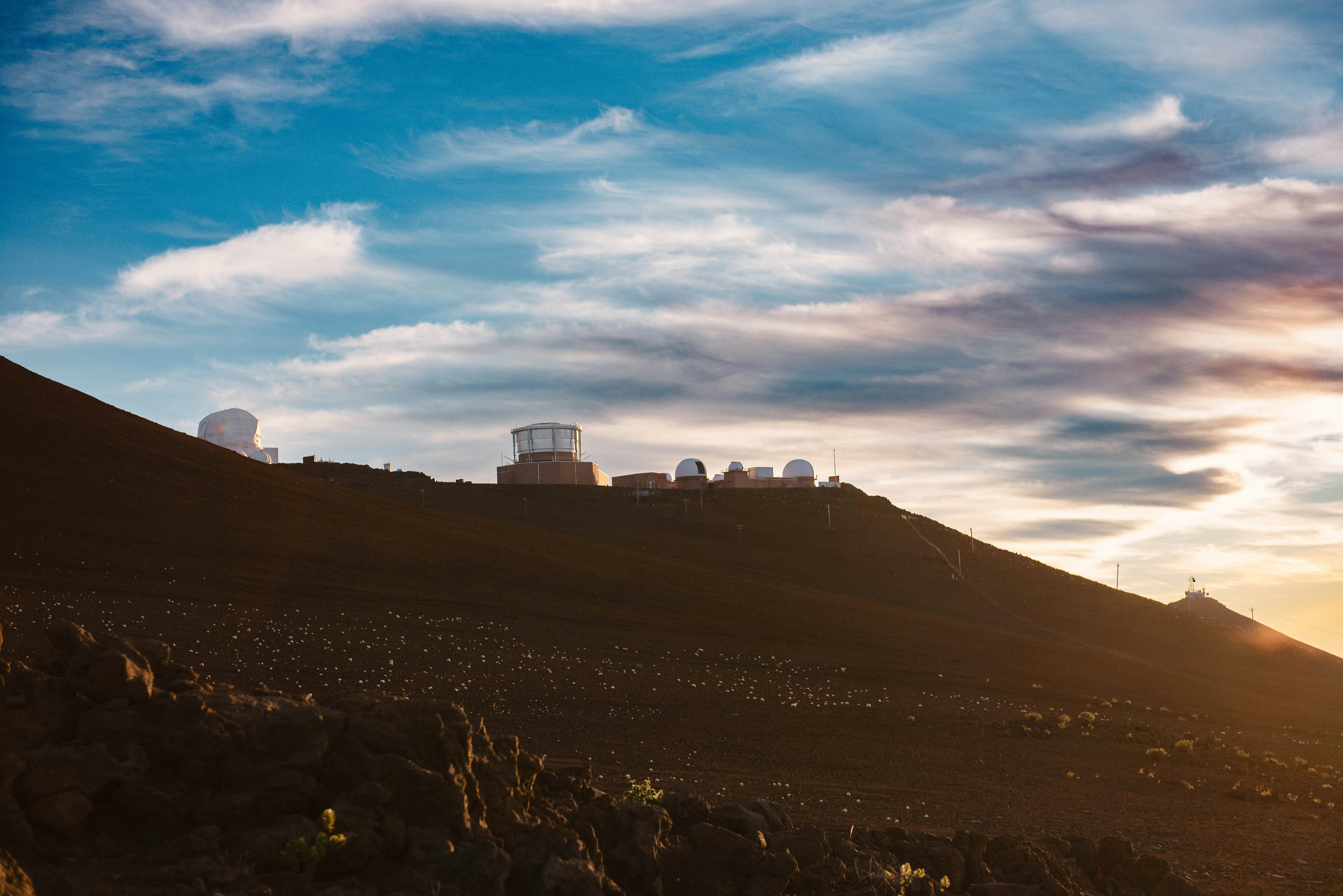 Observatories sit atop a mountain against a sunrise.
