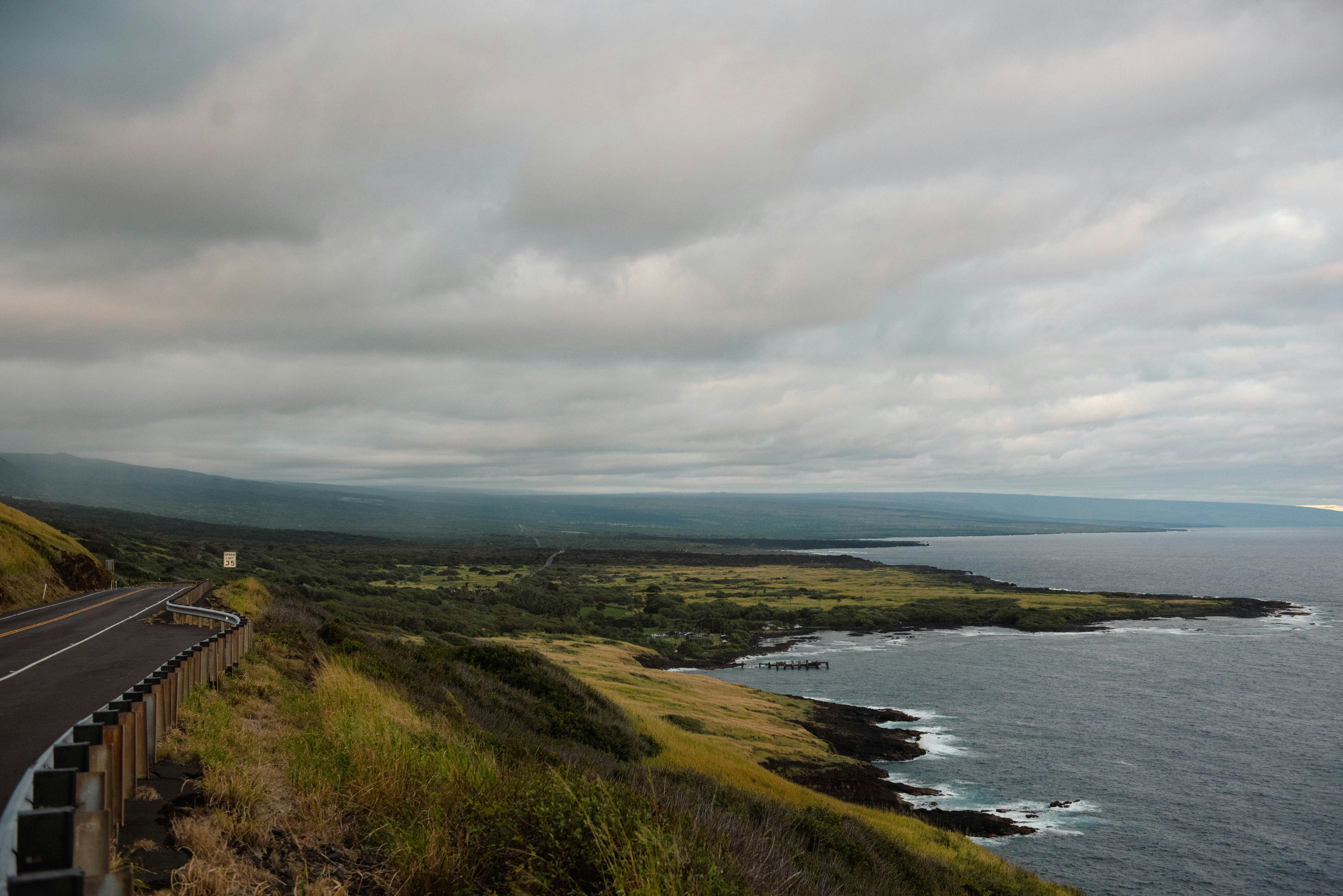 Road alongside the ocean under a cloudy sky.